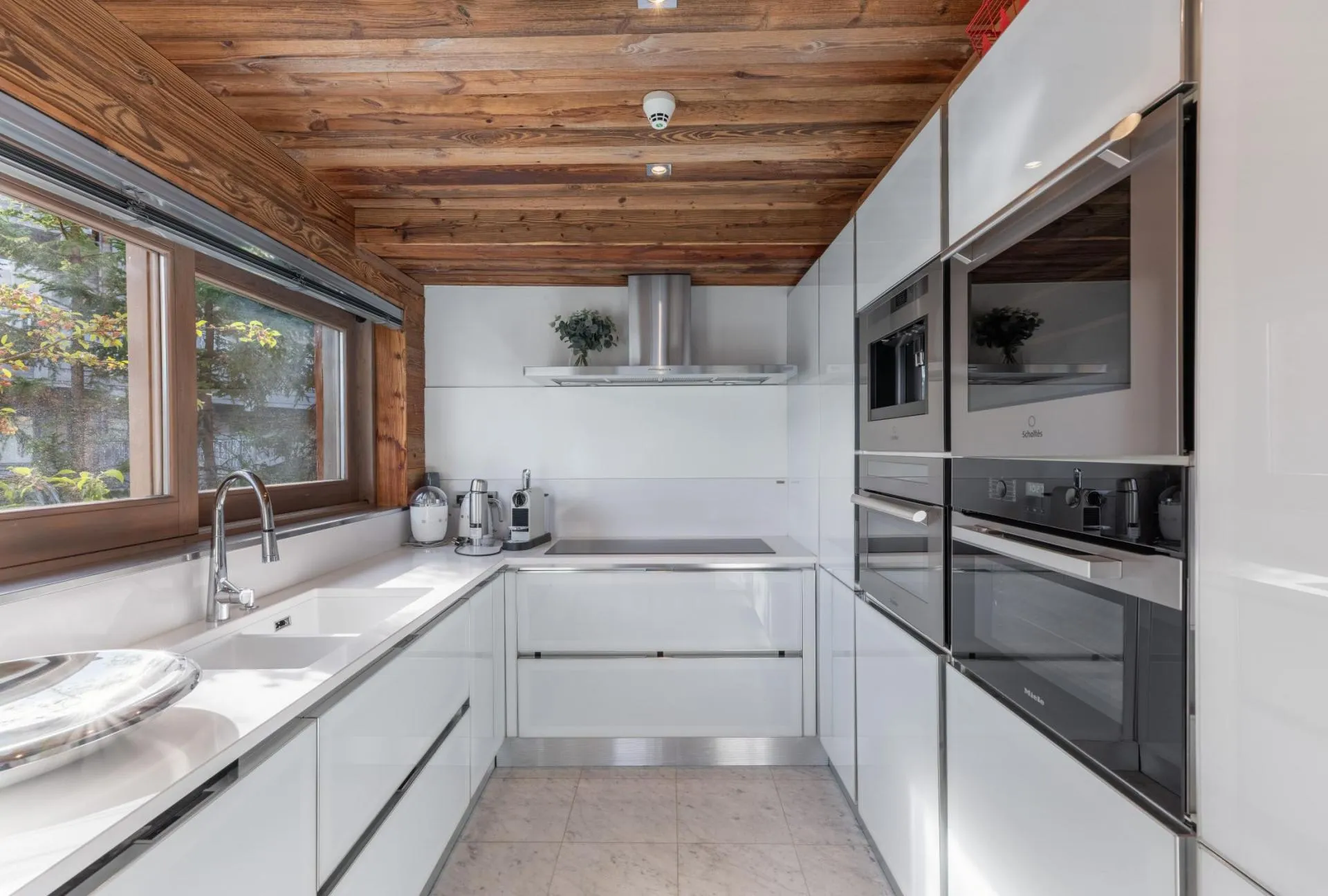 White fitted kitchen with stone worktops and timber ceiling
