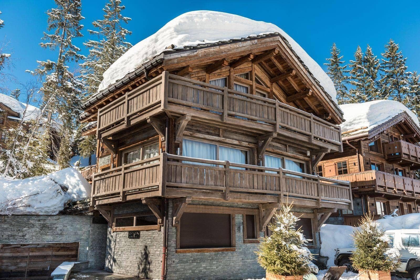 Ski-in chalet exterior featuring dual wrap-around balconies and stone foundation