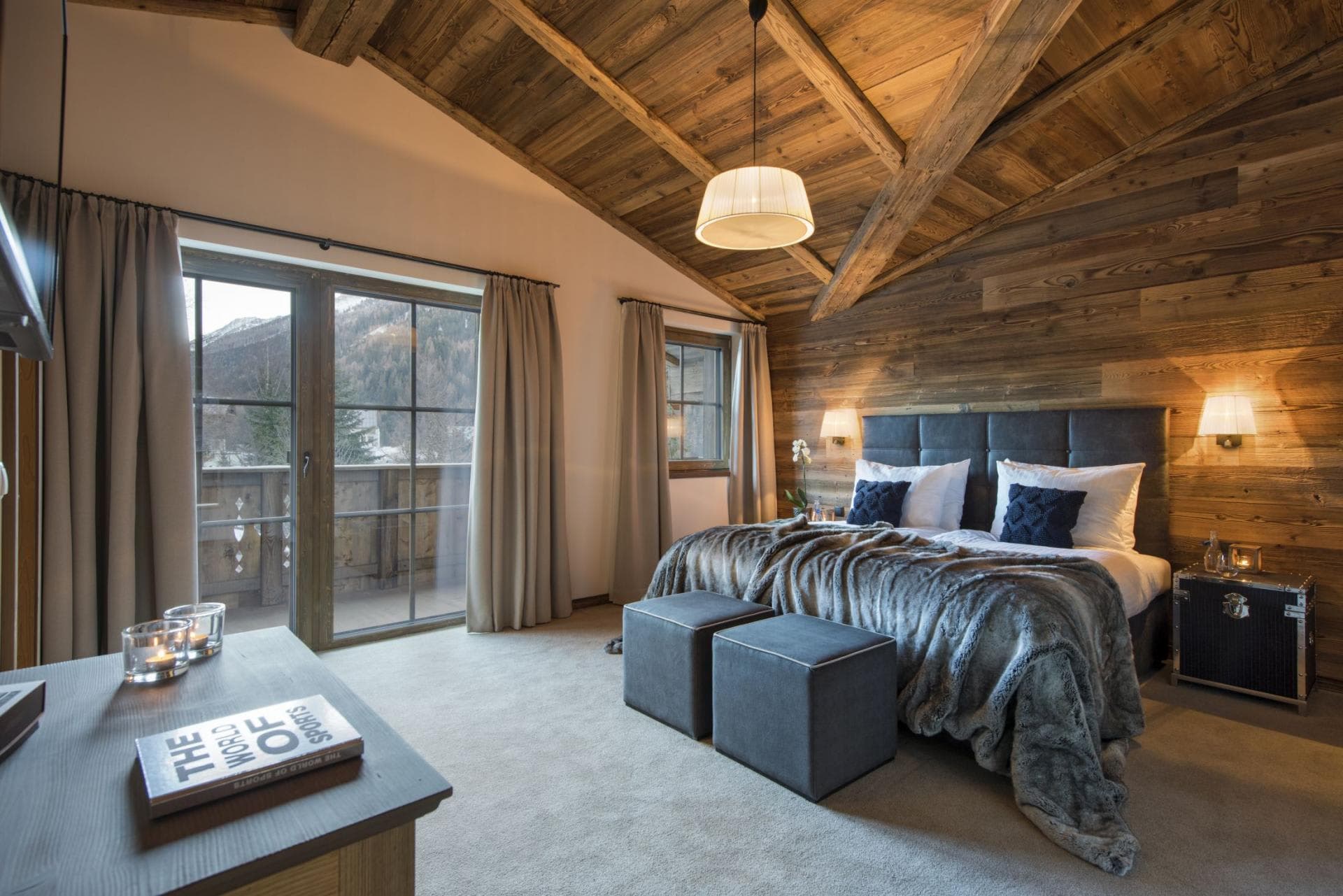 Primary bedroom with private balcony, mountain views, and vaulted timber ceiling
