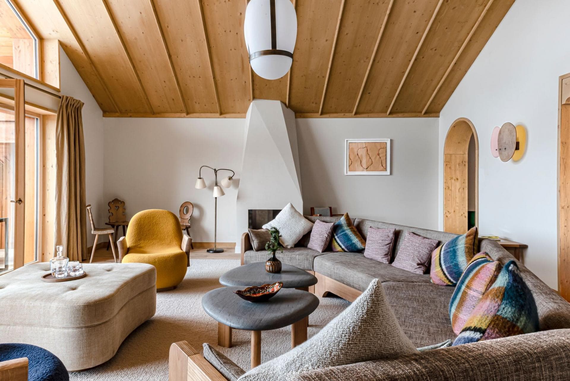 Living area with wood-paneled cathedral ceiling and sculptural wood-burning fireplace