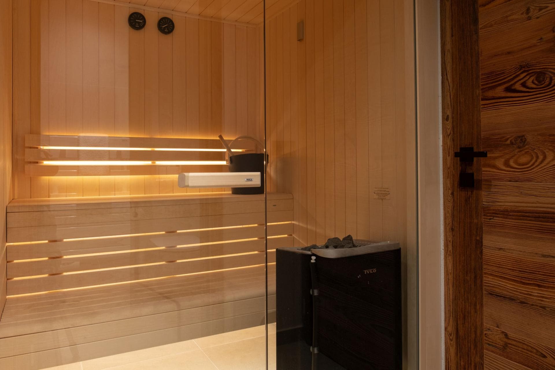 Private sauna with tiered wood seating and glass entry