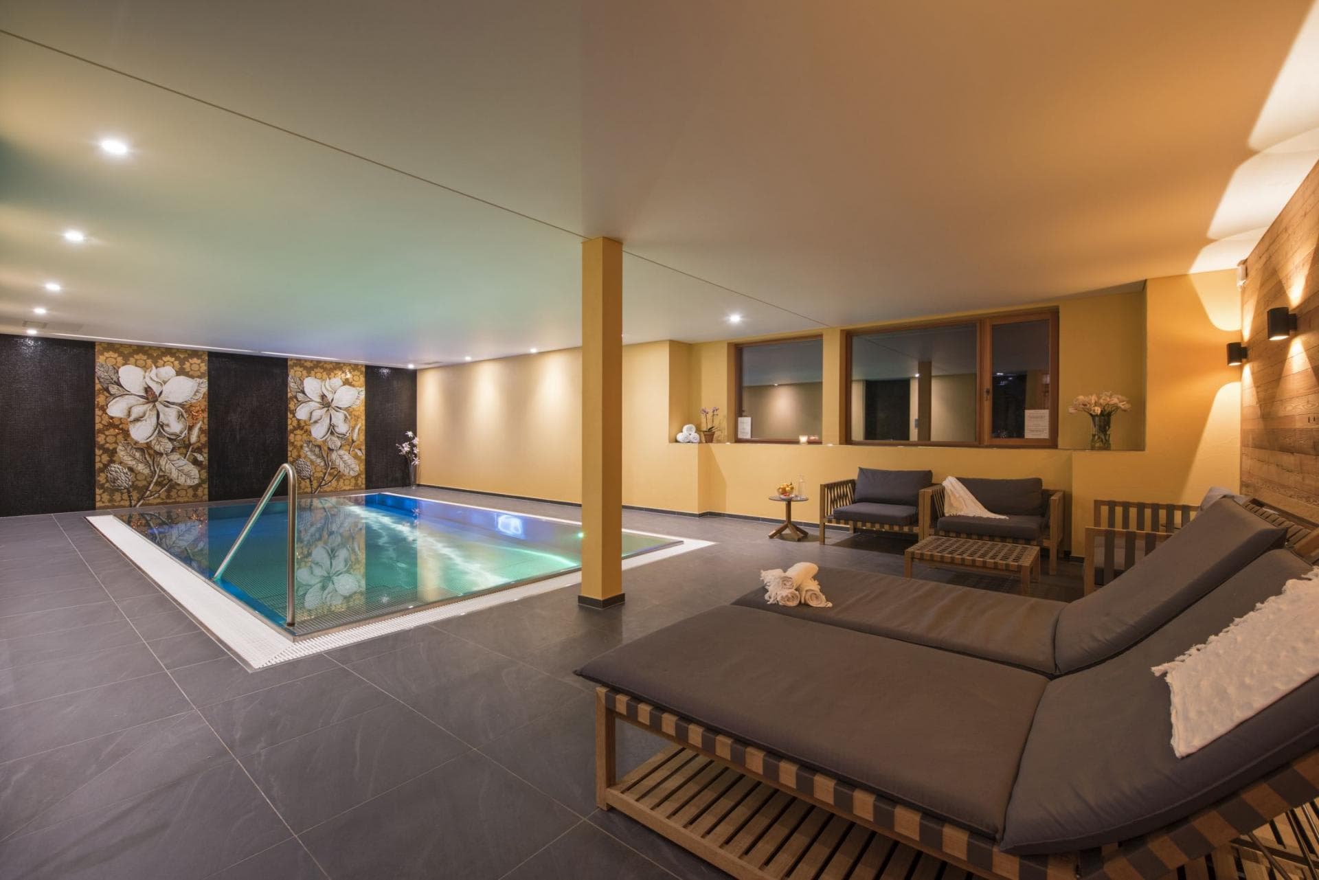 Indoor heated pool with lounge seating and adjacent sauna room