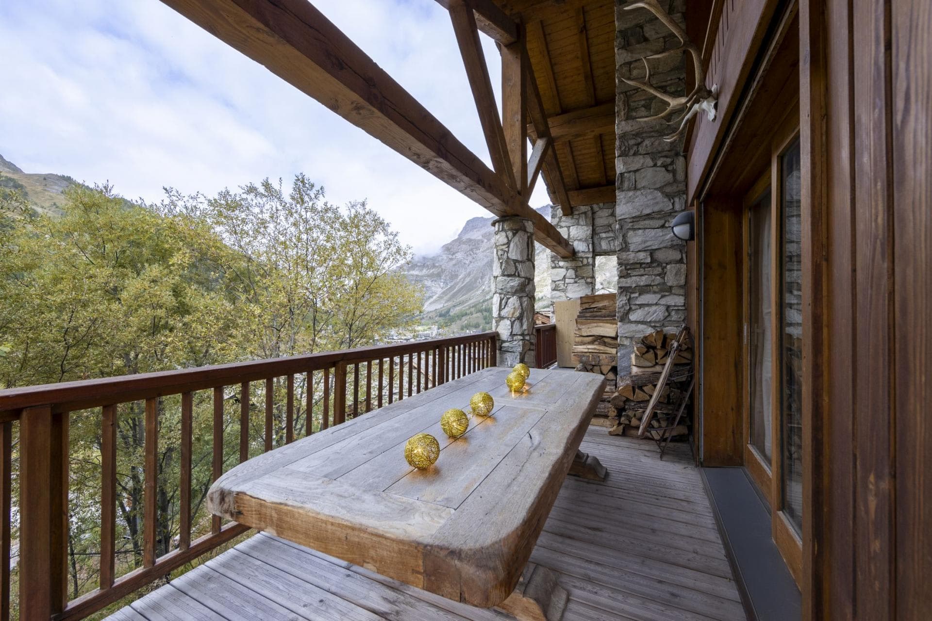 Covered balcony with wood-slab dining table and mountain views