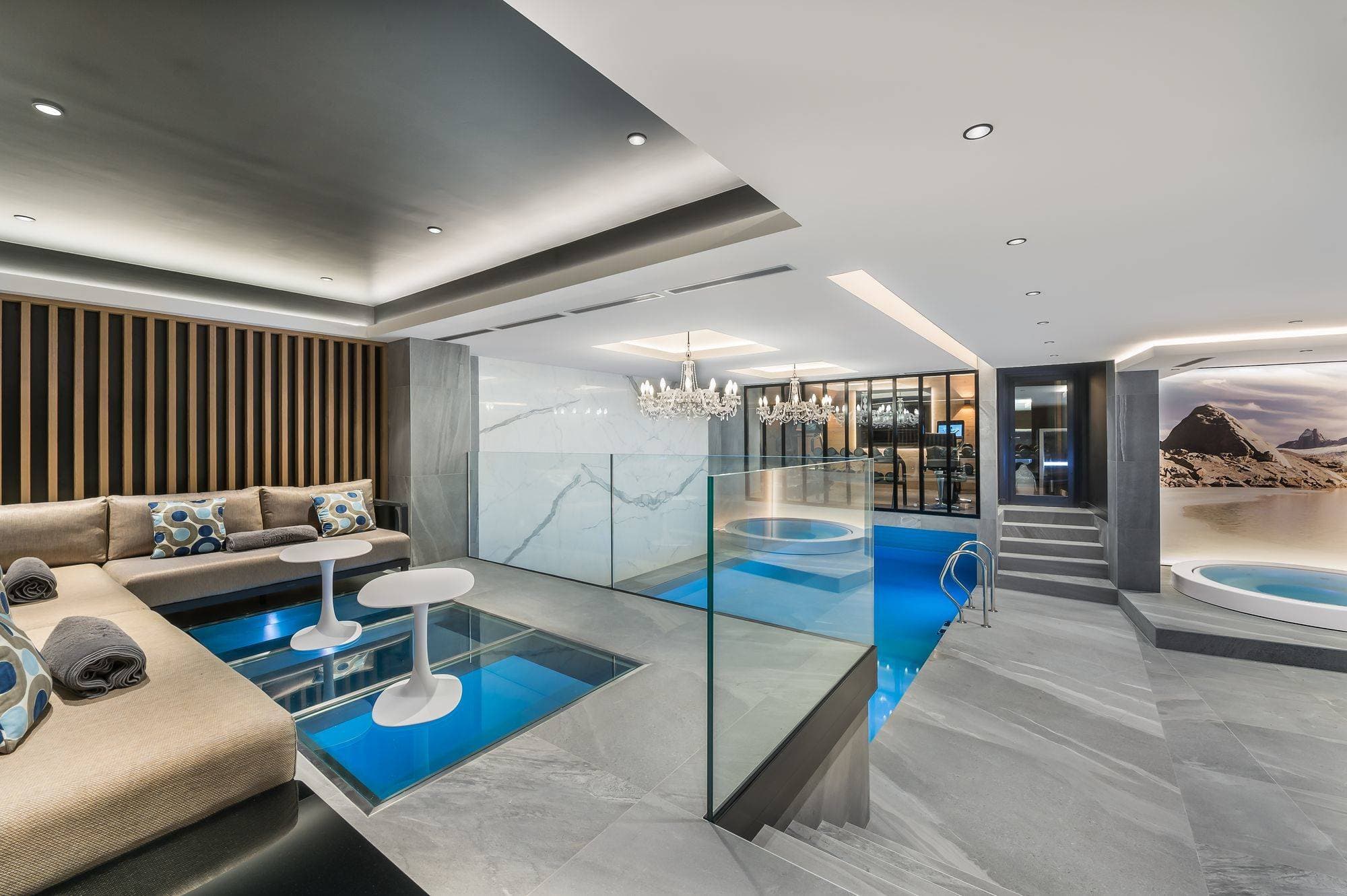 Indoor pool area with glass floor lounge and circular hot tub