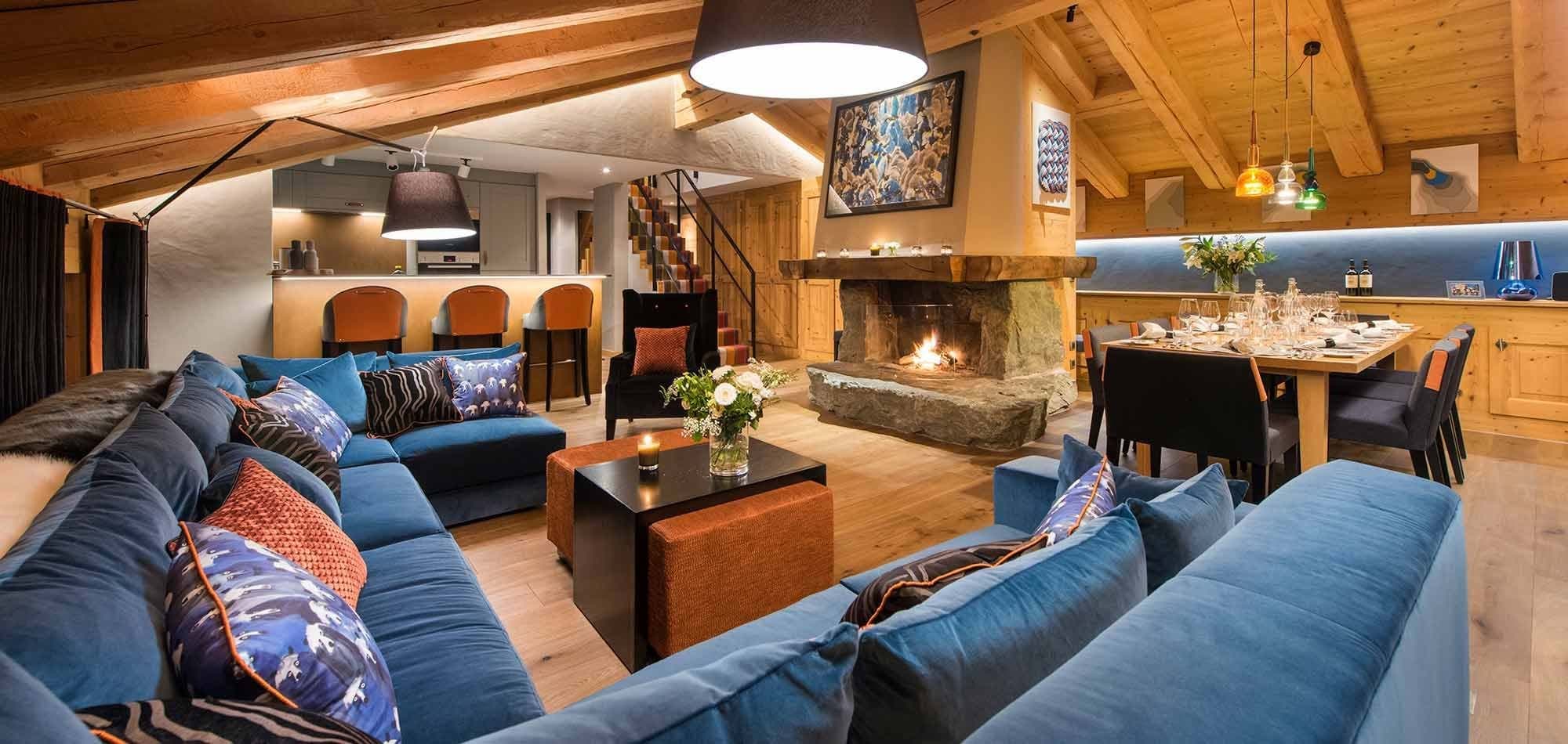 Open-plan living room with dual blue sectionals; fireplace and dining area seats 8