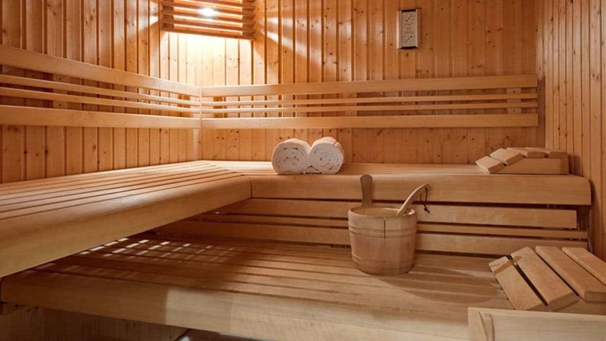 Sauna with multi-tier benches, rolled towels, and wooden bucket