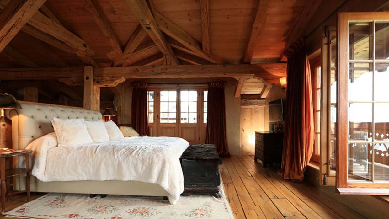 Primary bedroom with king bed, timber-framed ceiling, and balcony access