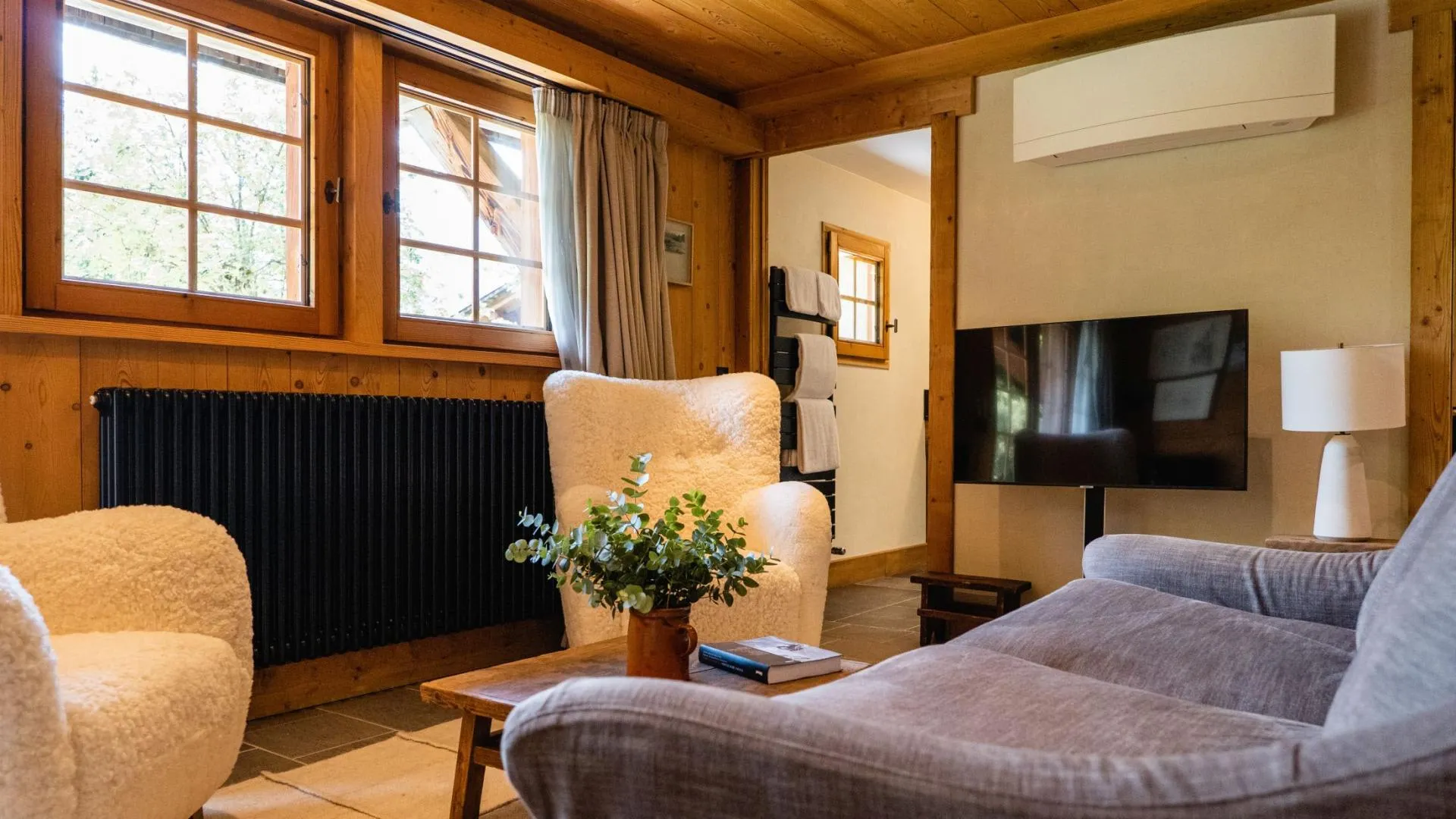 Living area with smart TV, air conditioning, and heated towel rack in hallway