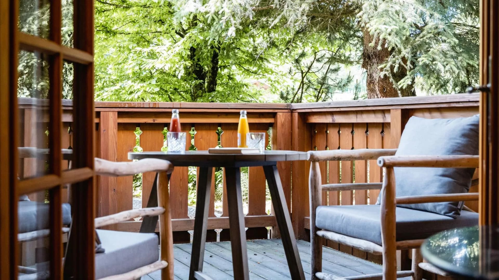 Private wooden balcony with cafe seating and shaded forest view