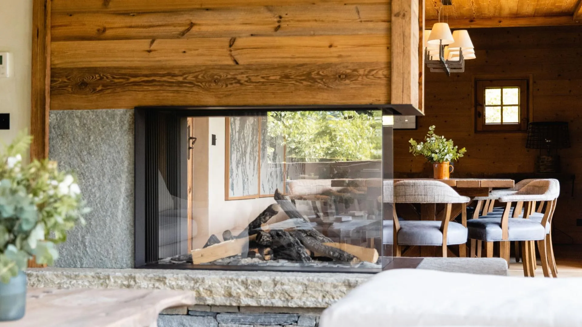 Double-sided glass fireplace connects the living area and dining room