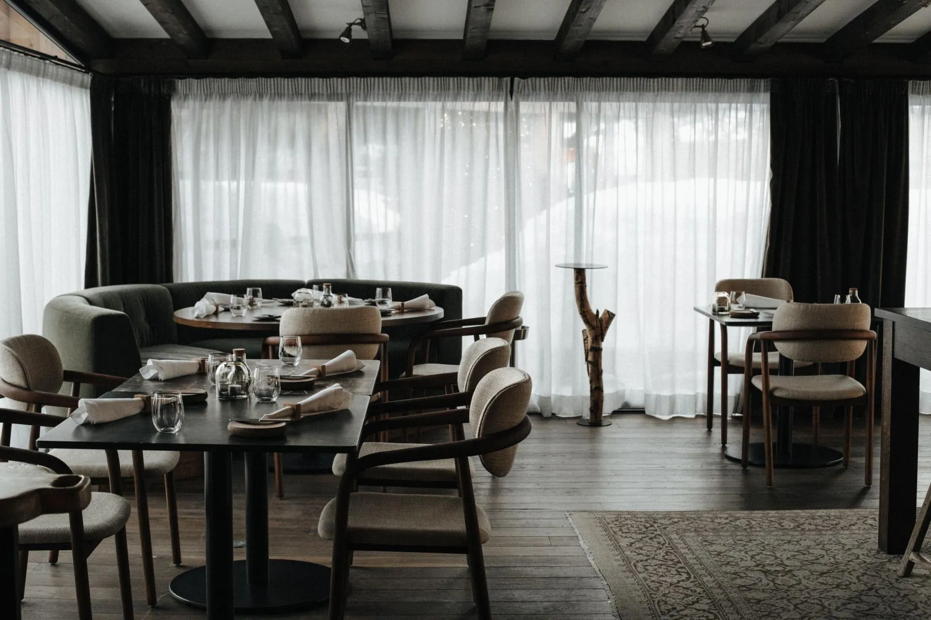 Dining area featuring curved banquet seating and dark wood beam ceilings