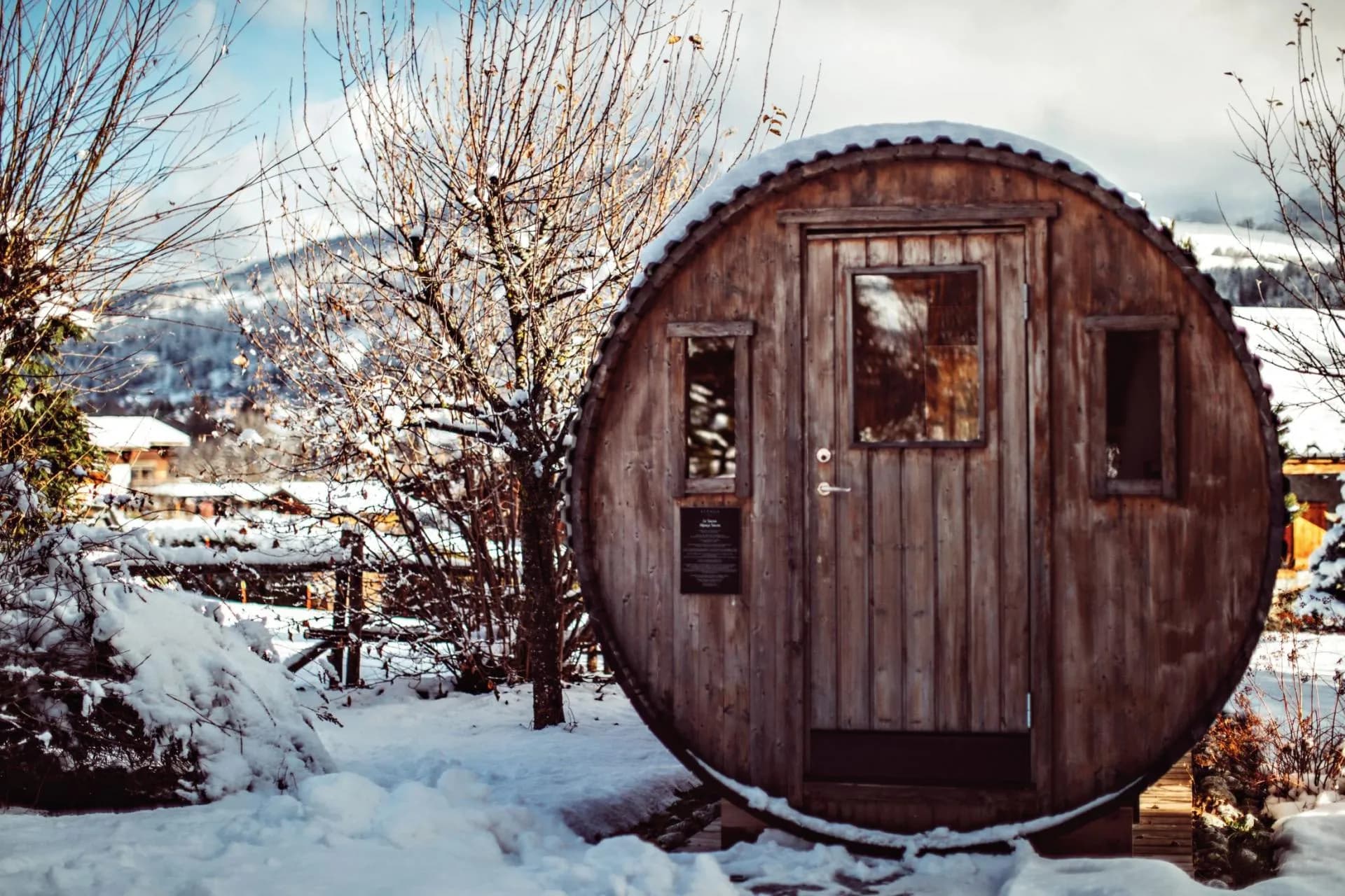 Outdoor barrel sauna with mountain views and snowy landscape