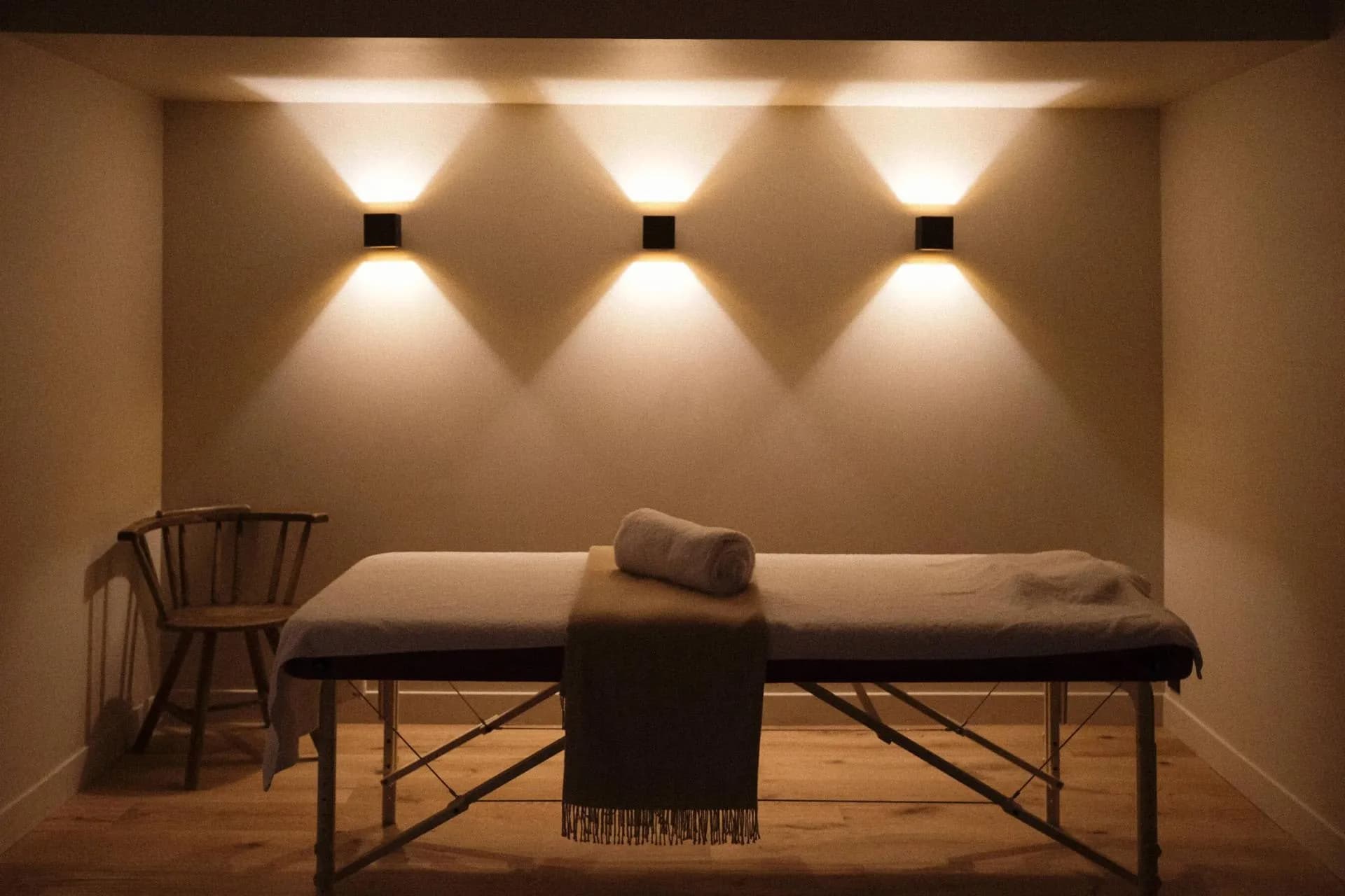 Private massage room with portable treatment table and dimmable sconce lighting