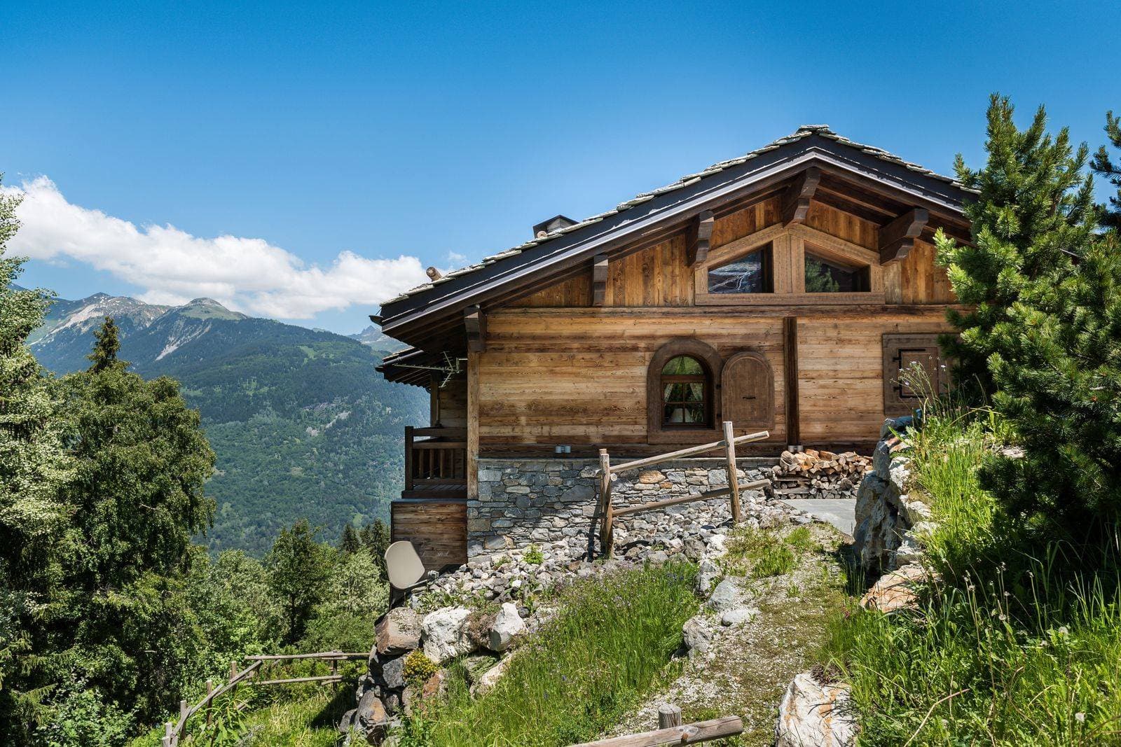 Timber chalet exterior with stone foundation and panoramic alpine valley views