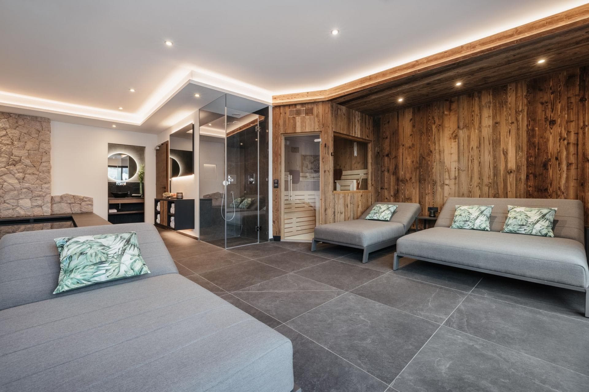 Private spa room with wood-paneled sauna, glass shower, and lounge seating