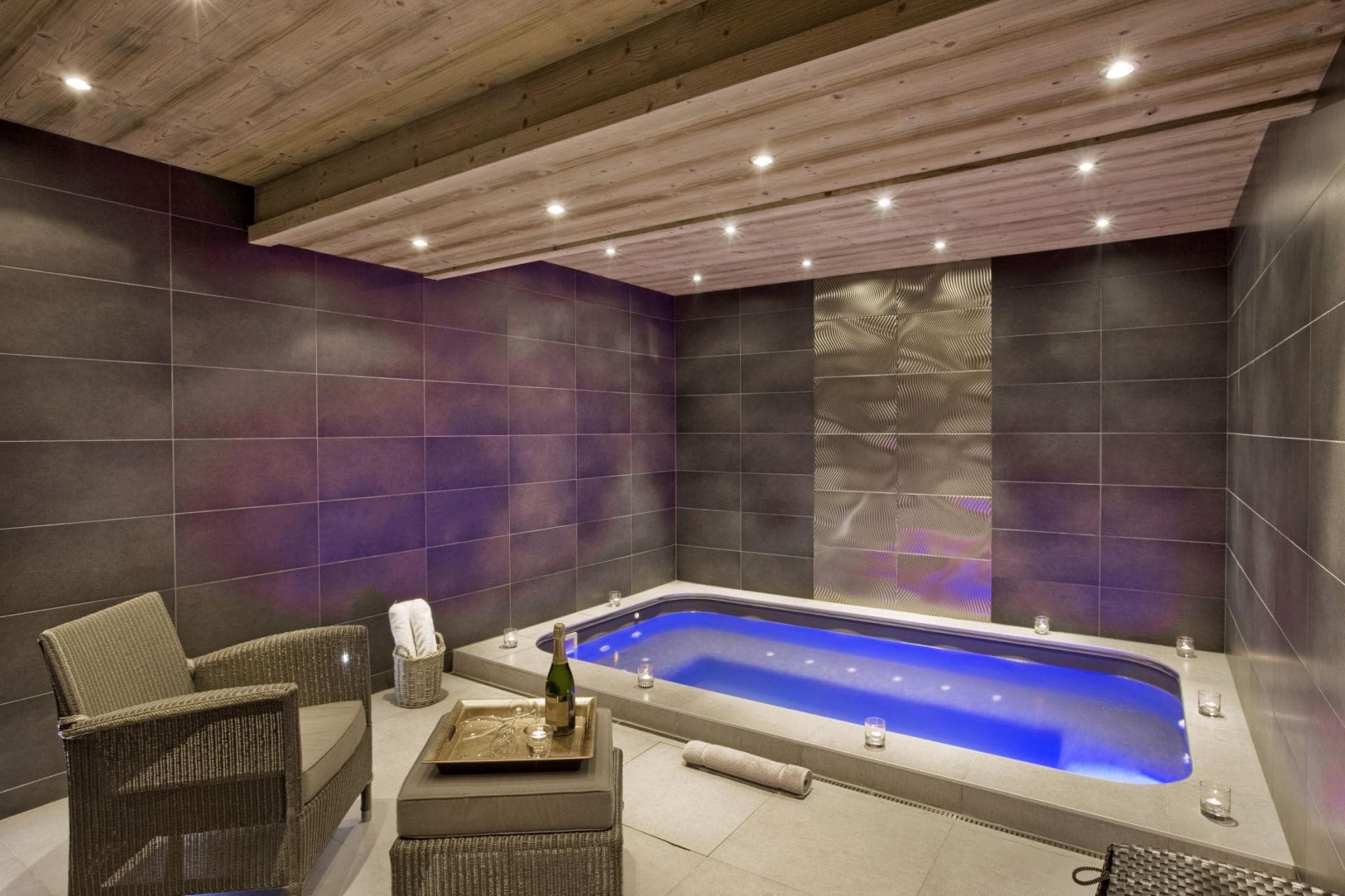 Indoor plunge pool with blue lighting and wood-paneled ceiling