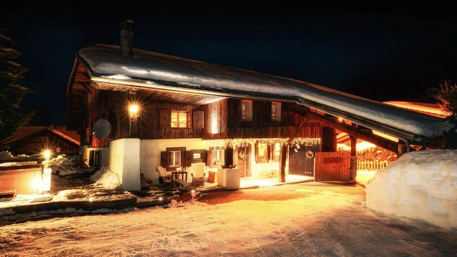 Chalet exterior at night with lit patio and bistro seating area
