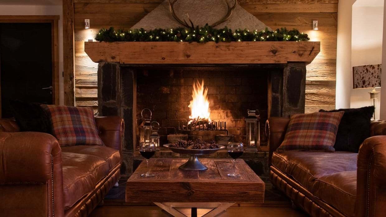 Wood-burning fireplace with reclaimed timber mantel and leather seating