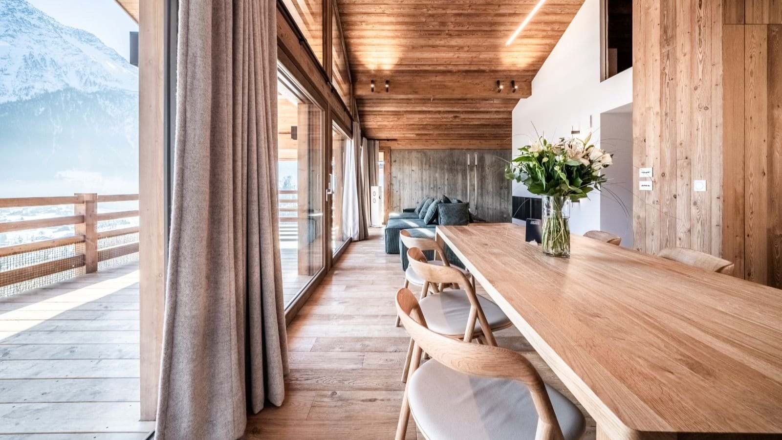 Open dining area with mountain-facing balcony and floor-to-ceiling windows