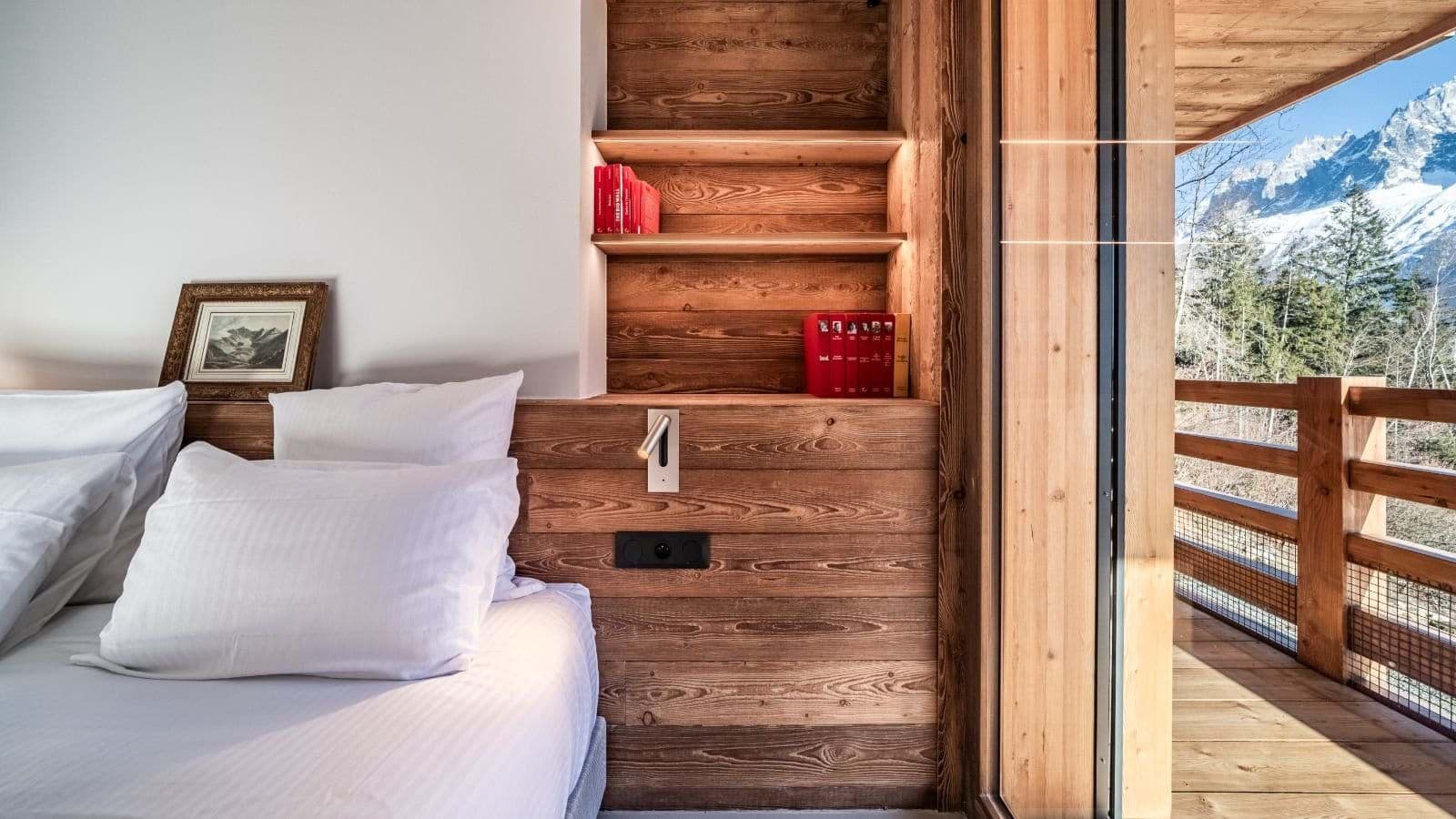 Bedroom with built-in reading light, shelving, and balcony access to mountain views