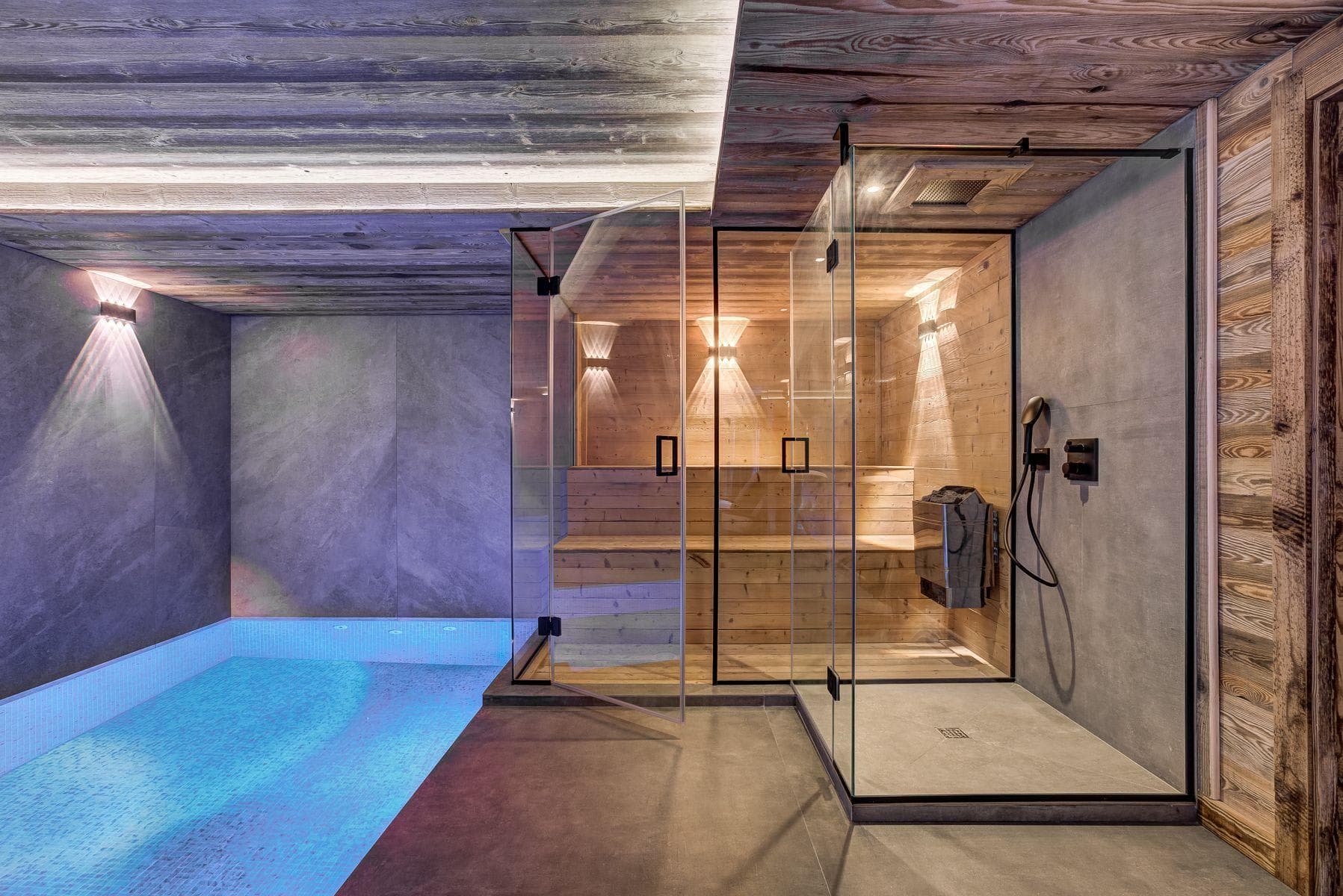 Indoor pool area with glass-enclosed sauna and walk-in rain shower