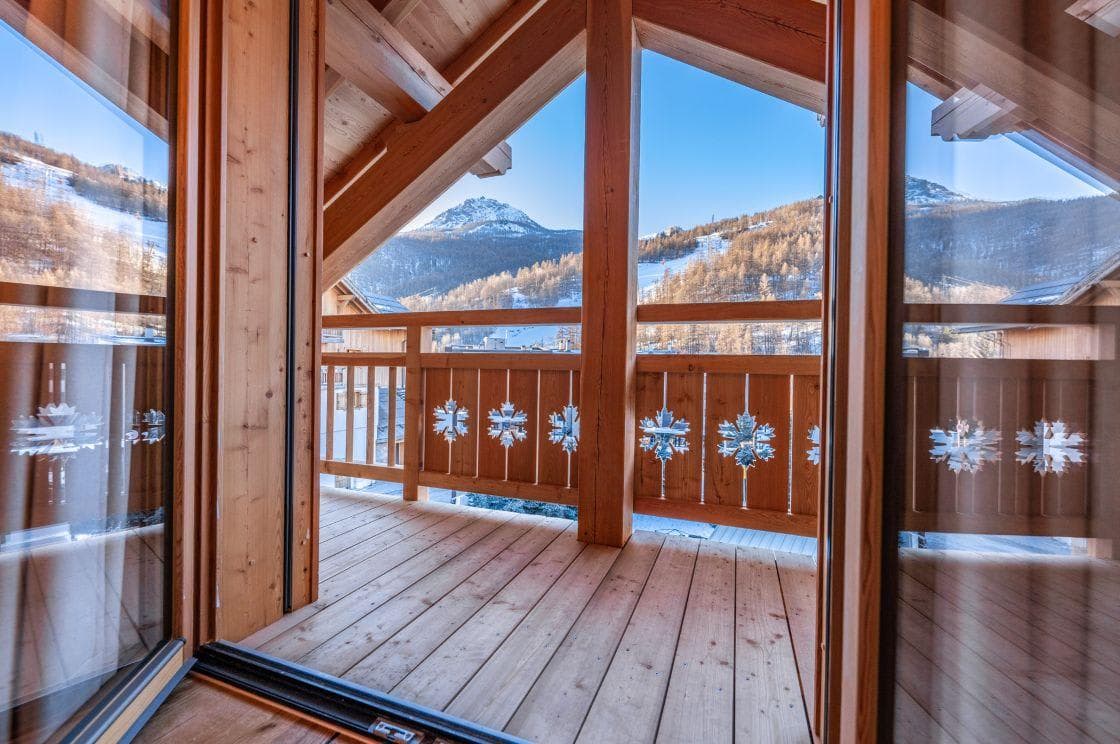 Covered timber balcony with mountain views and snowflake railing detail