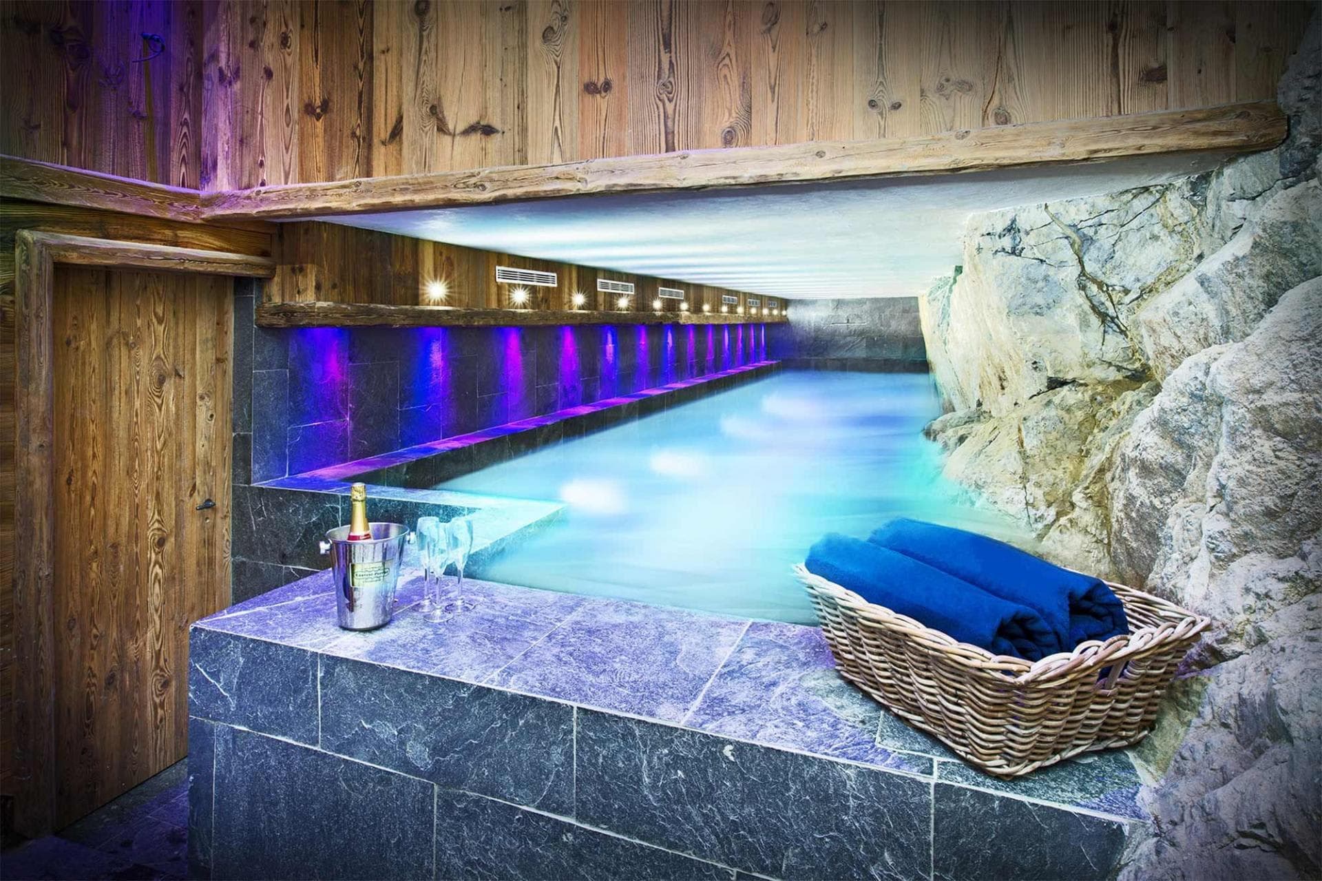 Indoor lap pool featuring natural rock wall and ambient lighting