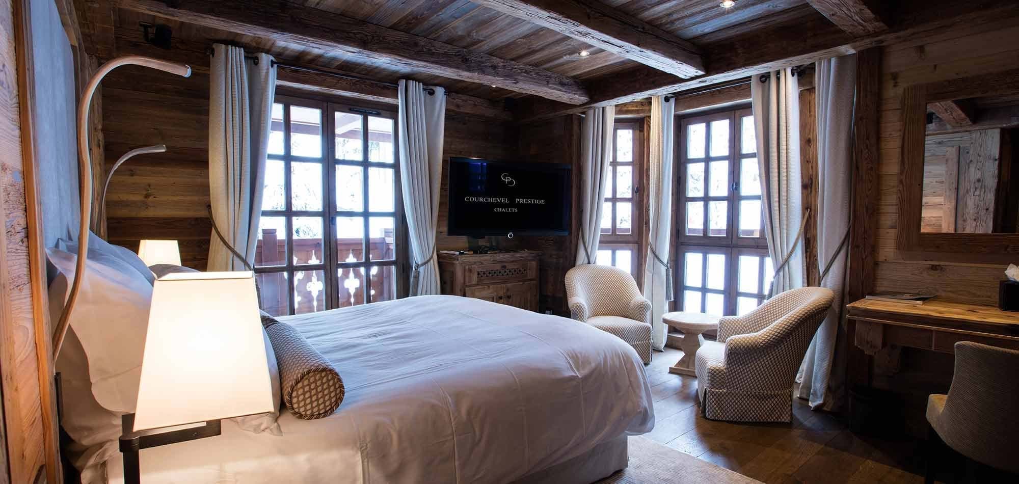 Wood-paneled bedroom with king bed, balcony access, and sitting area