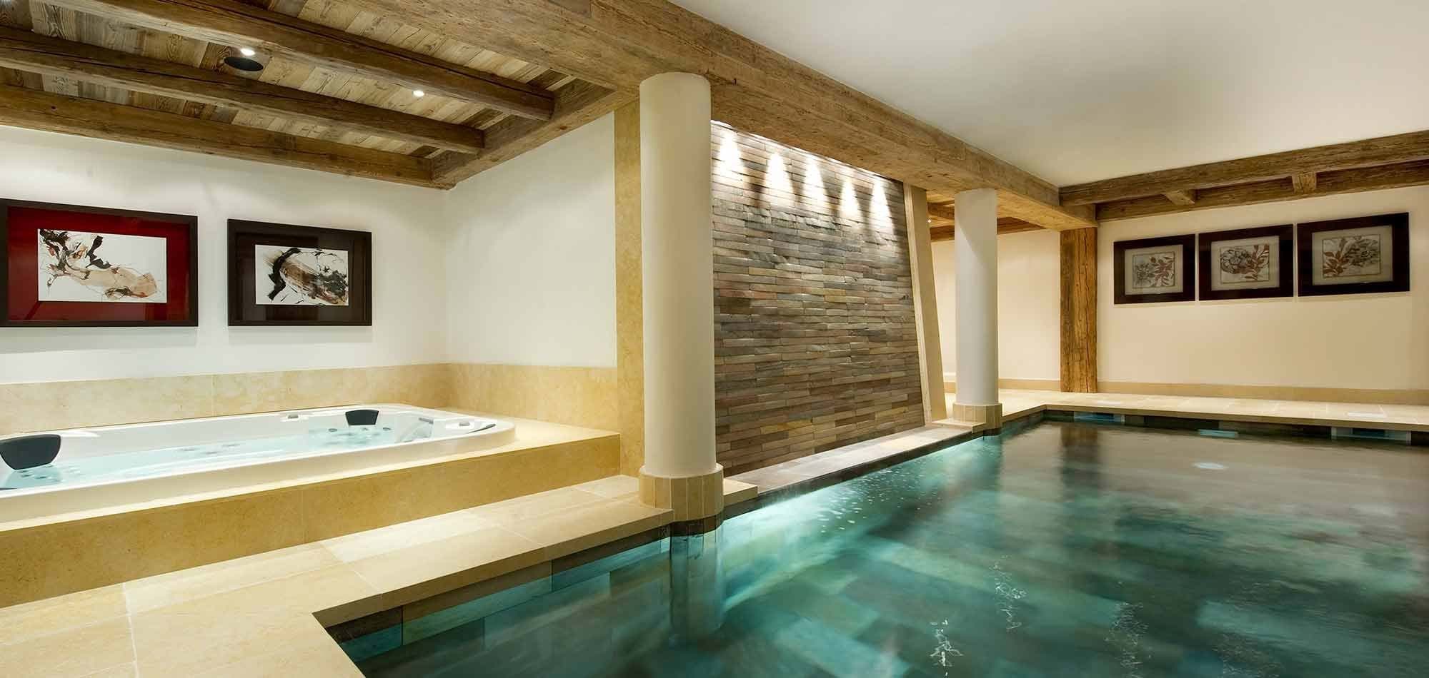 Indoor heated pool and adjacent jetted hot tub with stone accents