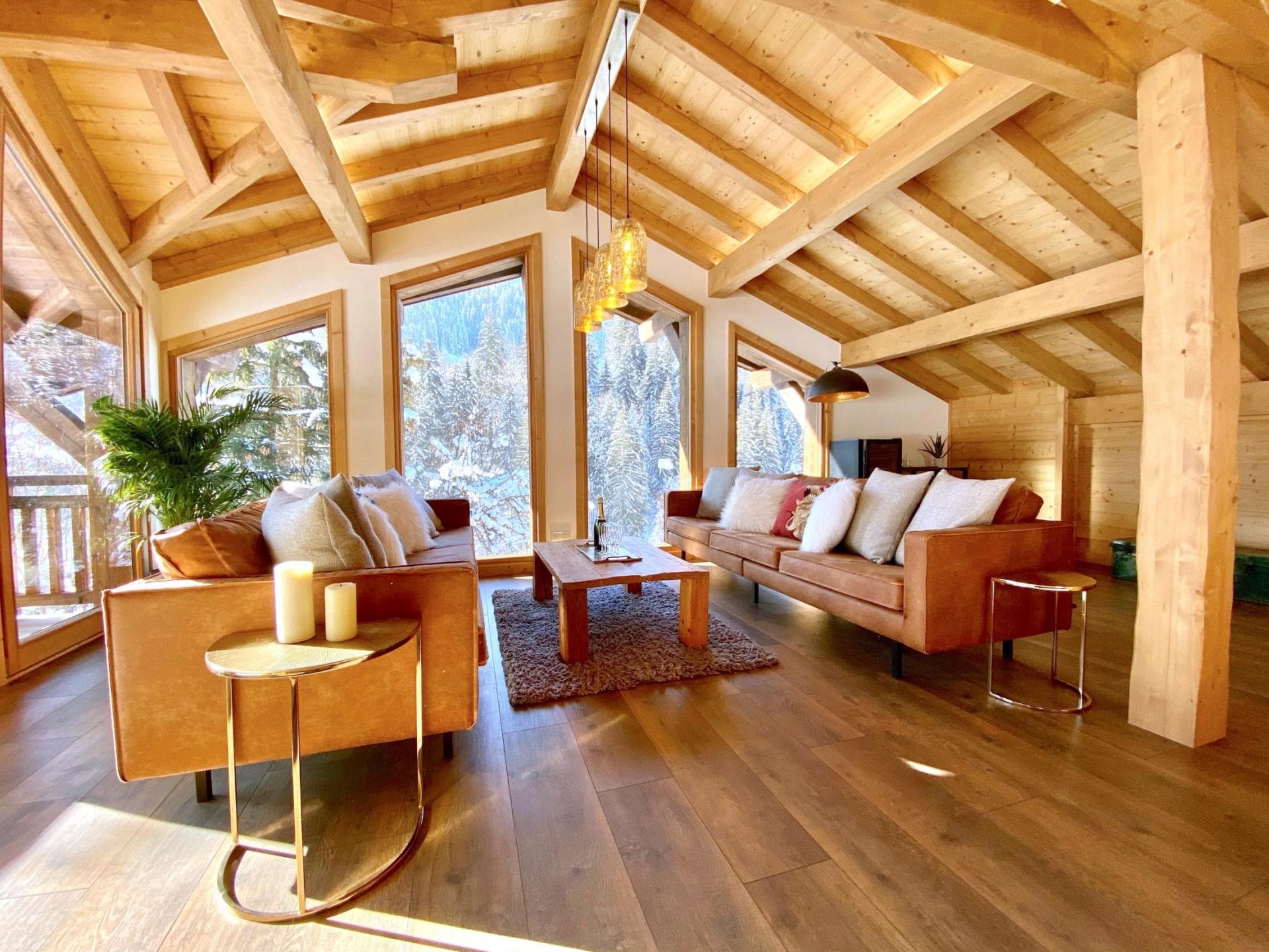 Living area with vaulted timber ceilings and floor-to-ceiling forest views