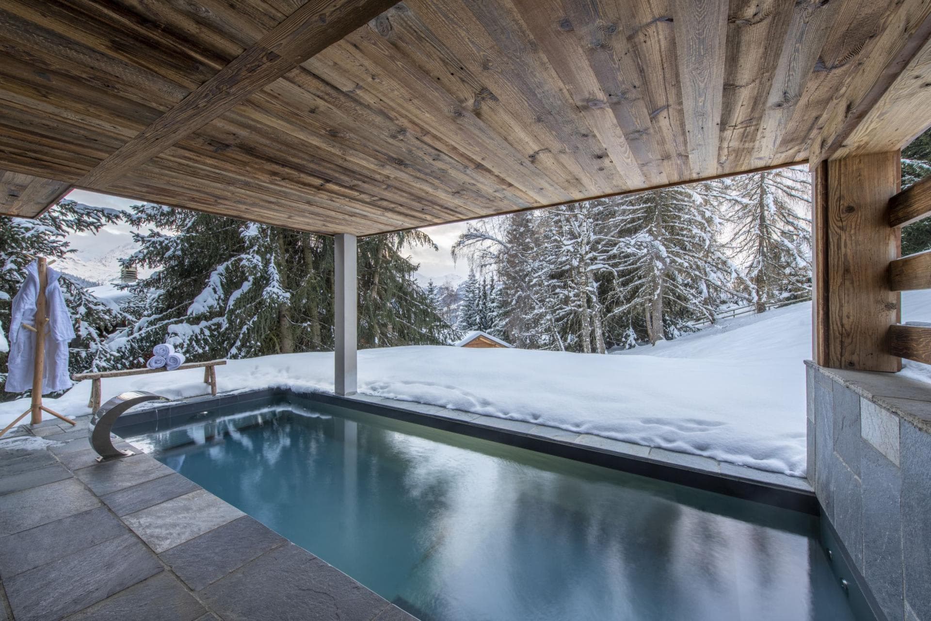 Covered outdoor plunge pool with swan neck fountain and forest views