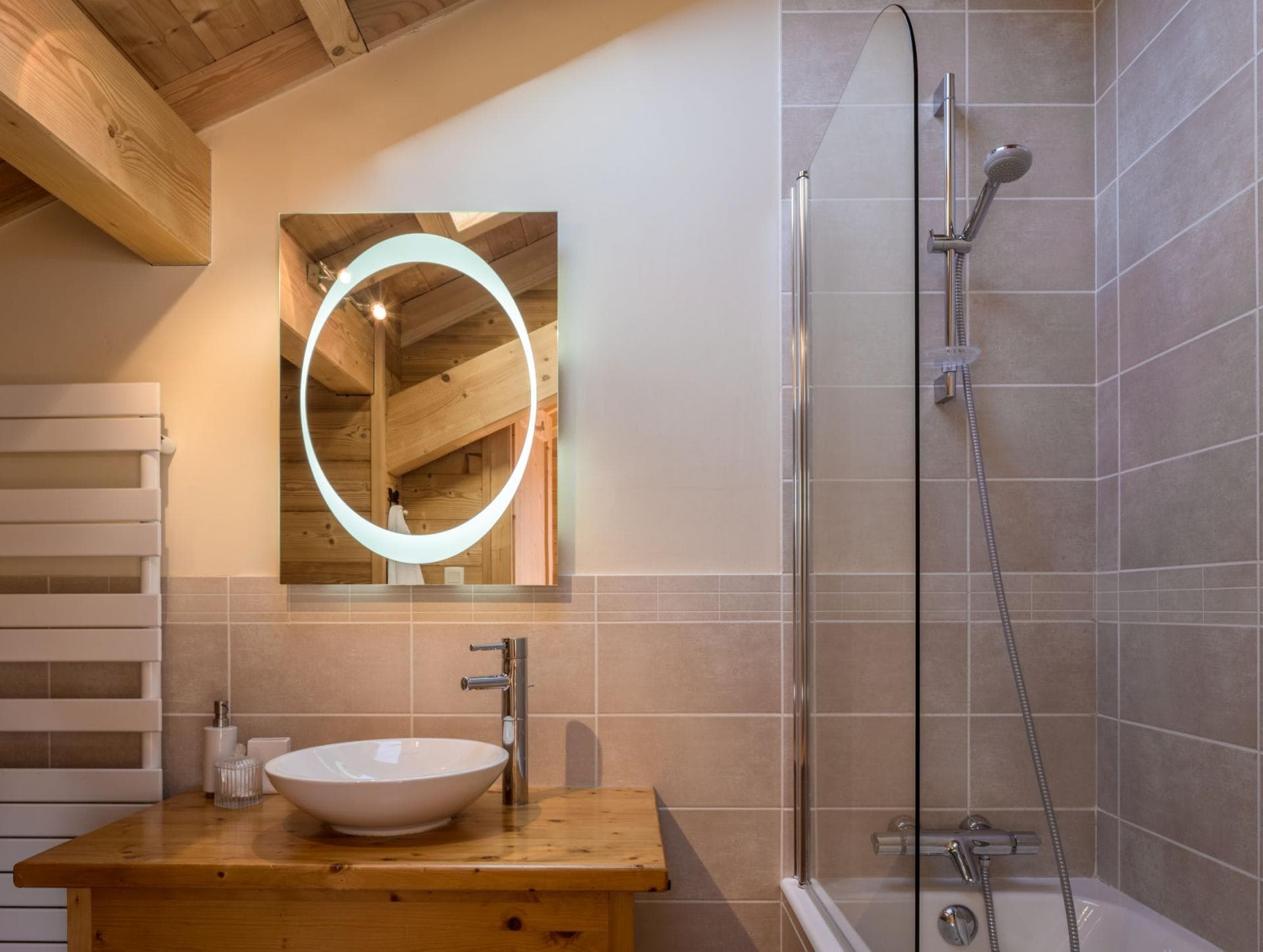 Bathroom with heated towel rail, backlit mirror, and glass-screened bathtub