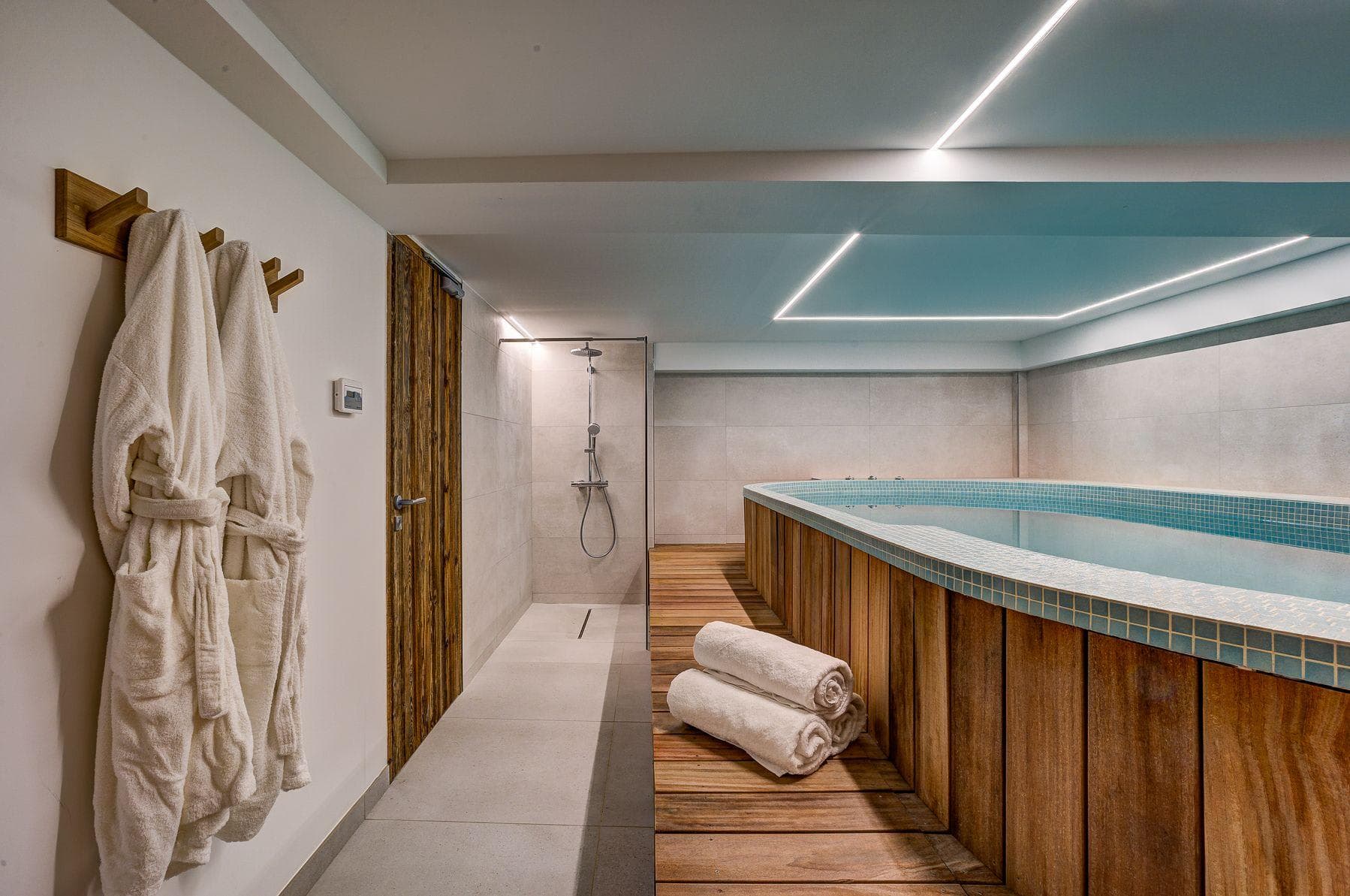 Indoor plunge pool with wood decking and walk-in rainfall shower
