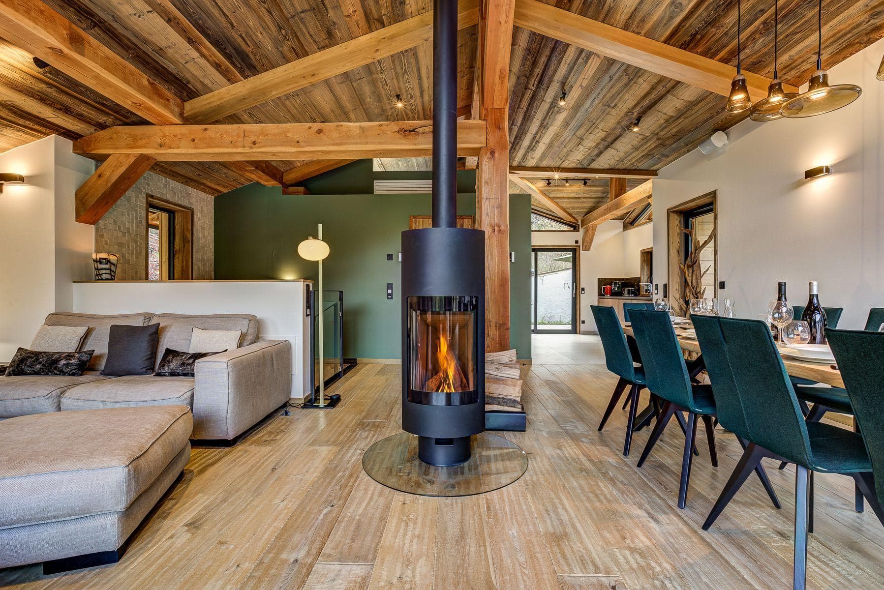 Open-plan living area with 360-degree wood-burning fireplace and exposed timber beams