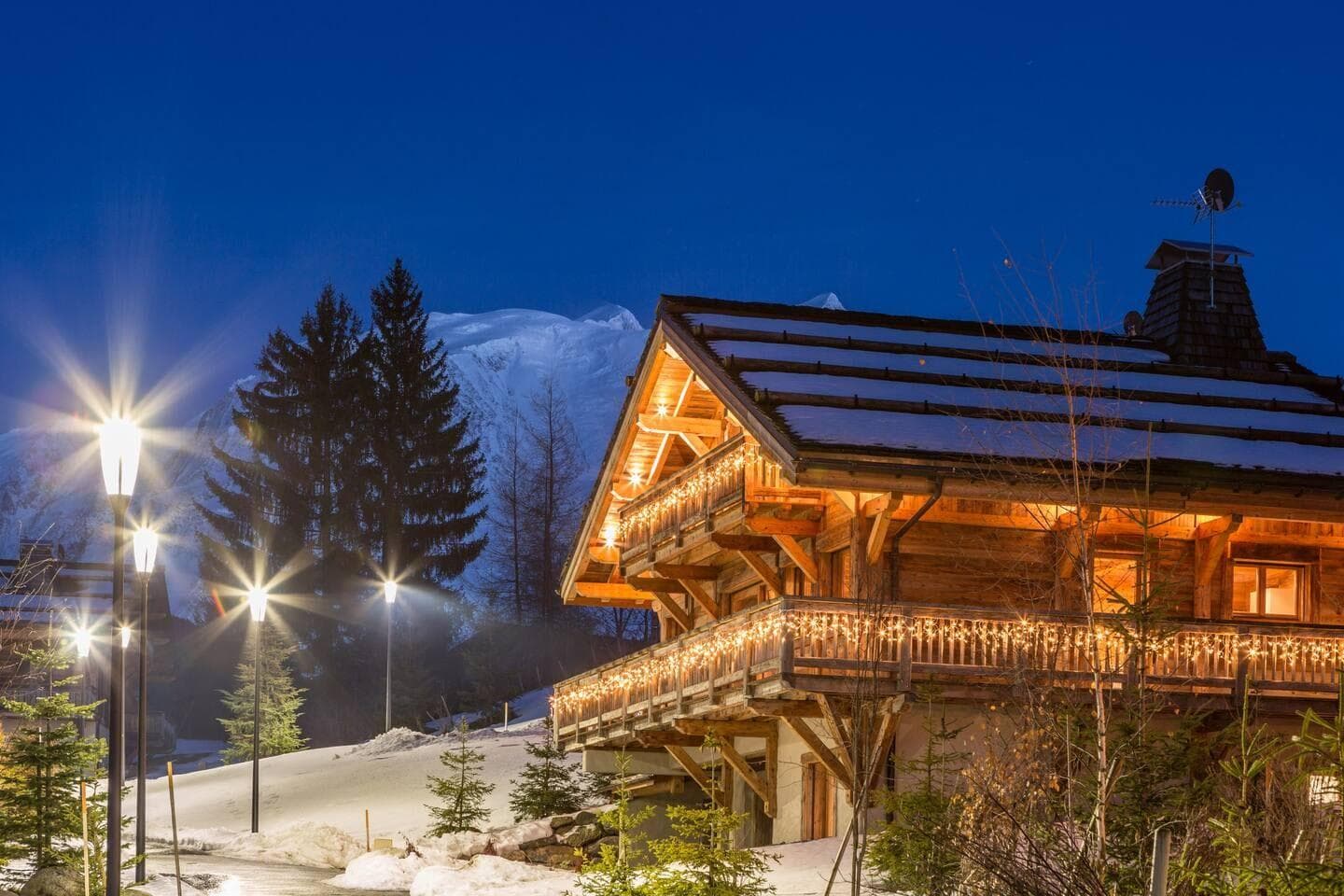 Chalet exterior at dusk with wrap-around balconies and mountain views