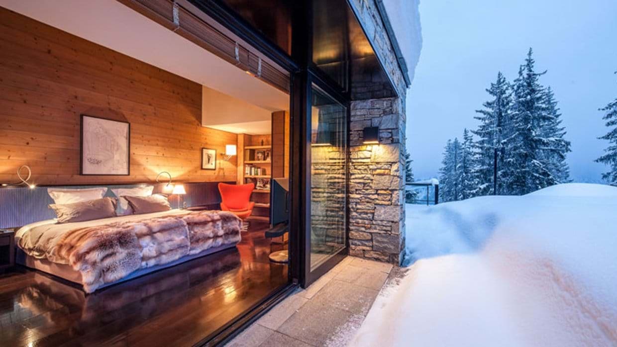 Primary bedroom with king bed and floor-to-ceiling glass doors for direct snow access