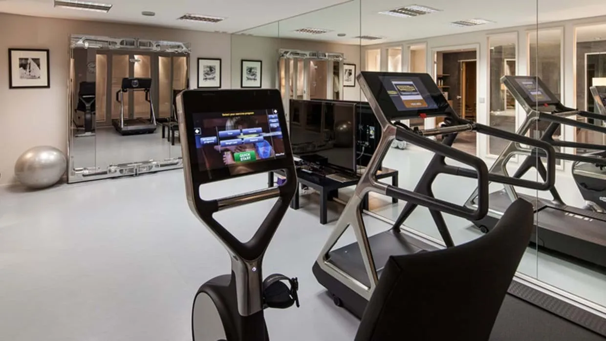 Private gym with Technogym treadmill, exercise bike, and floor-to-ceiling mirrors