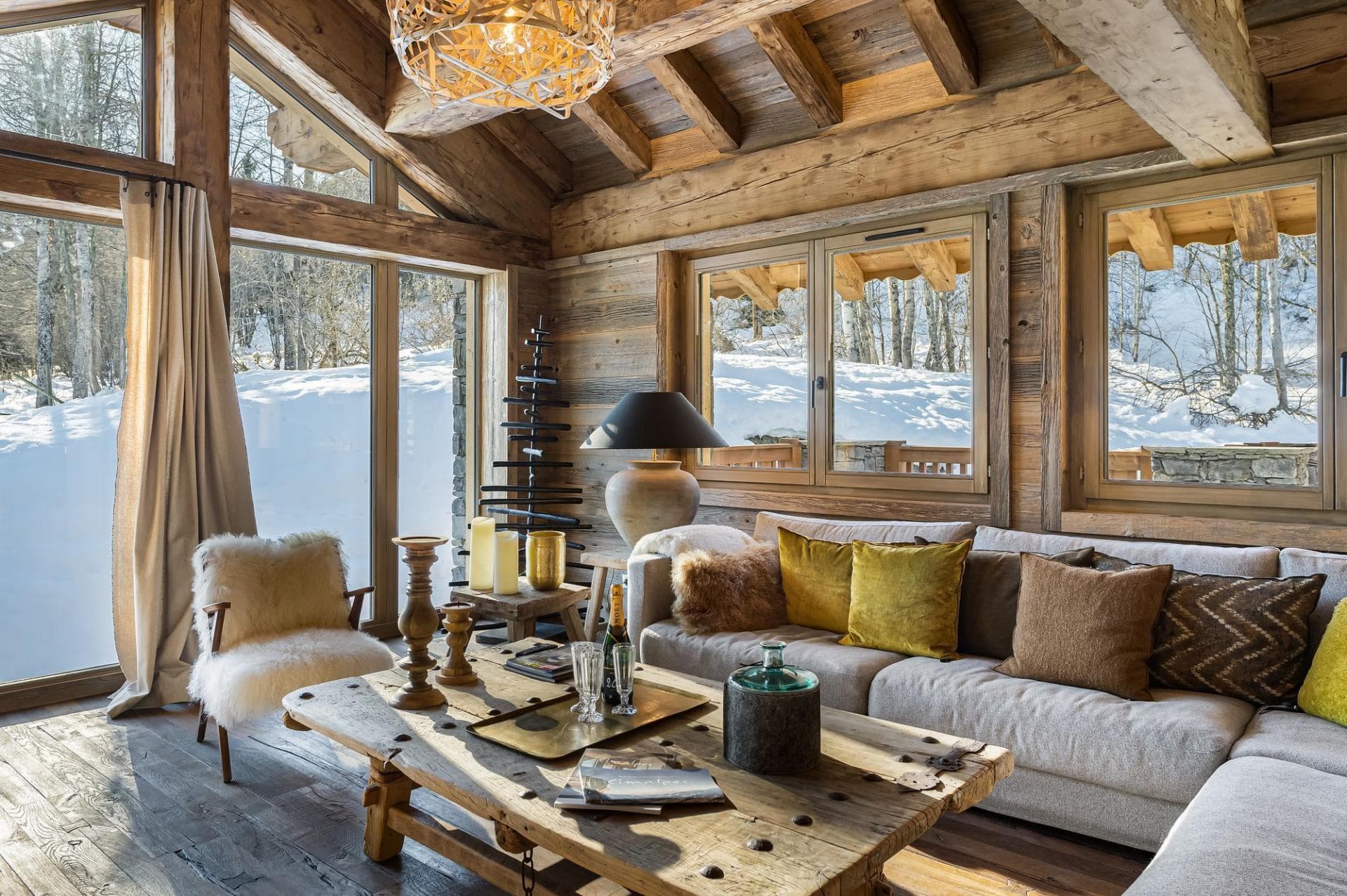 Living area with reclaimed wood beams and floor-to-ceiling snow views