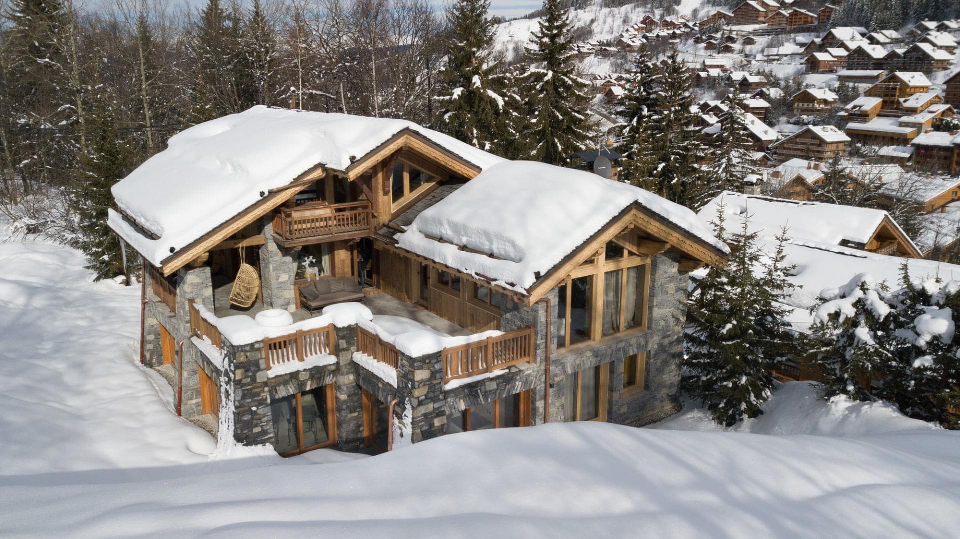 Ski-in chalet with multi-level stone terraces and hanging egg chair