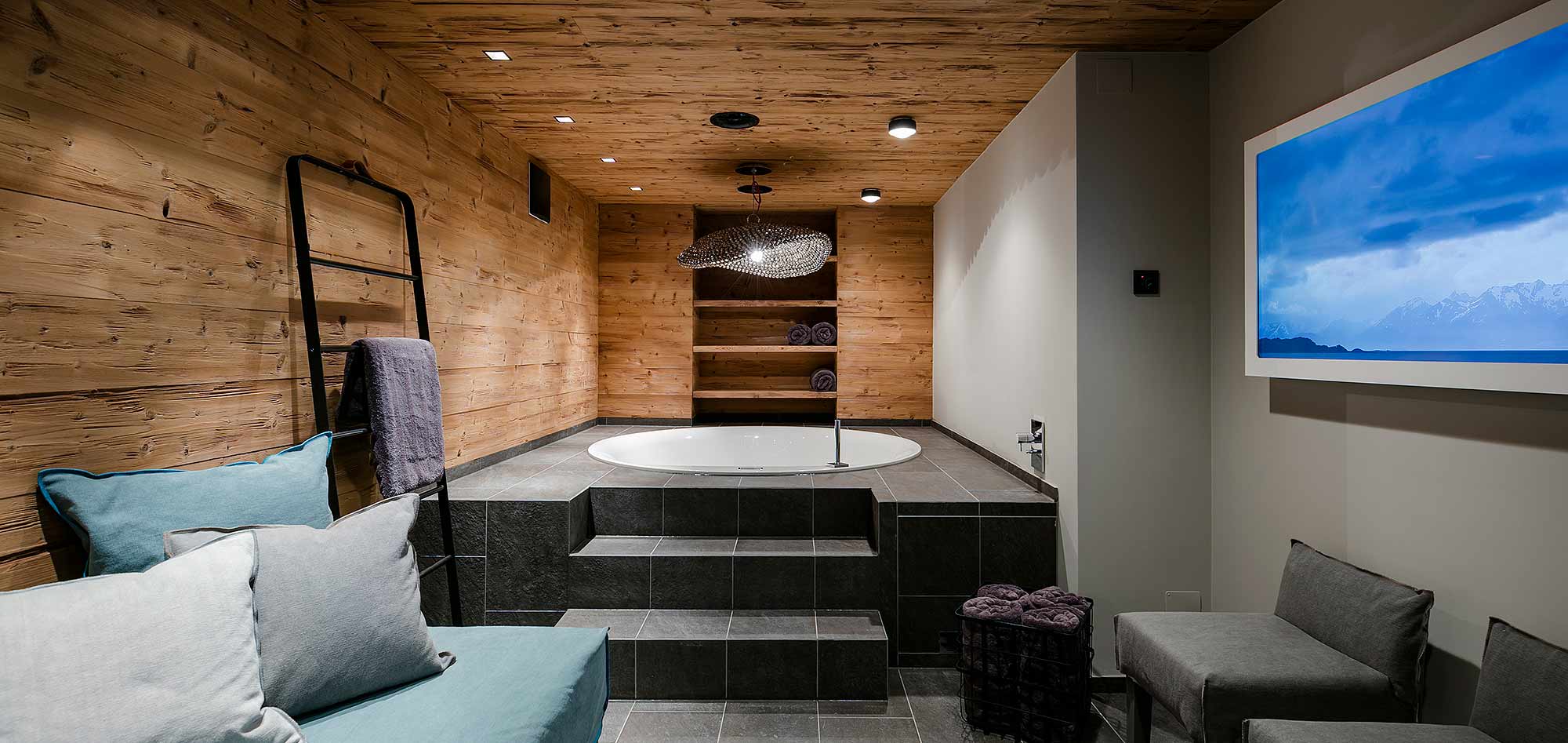 Indoor spa room with jetted tub and wall-mounted screen