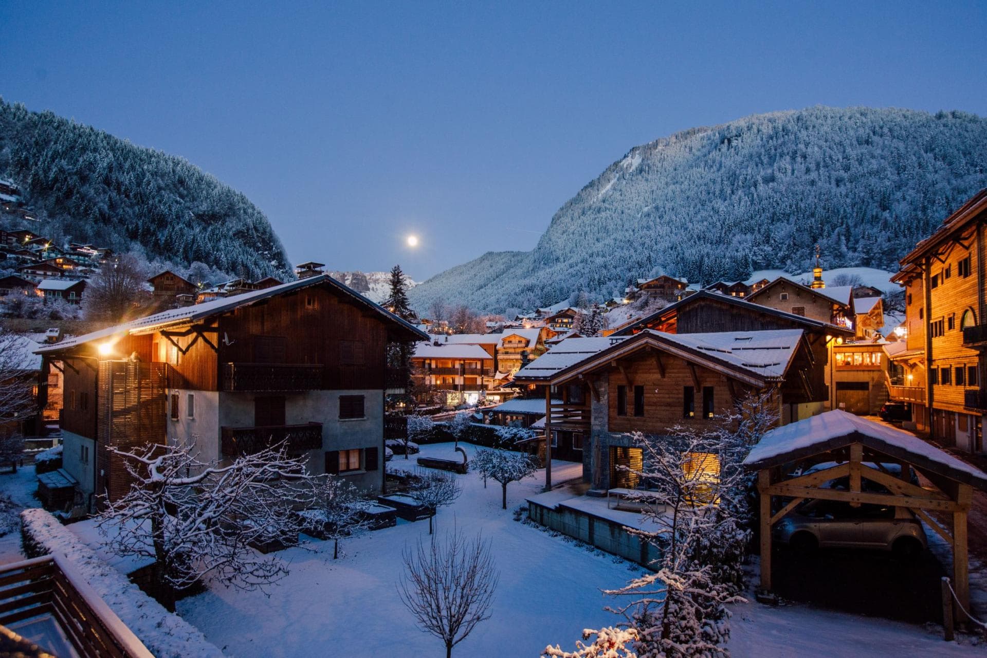Balcony view of alpine village and snow-covered mountains at dusk