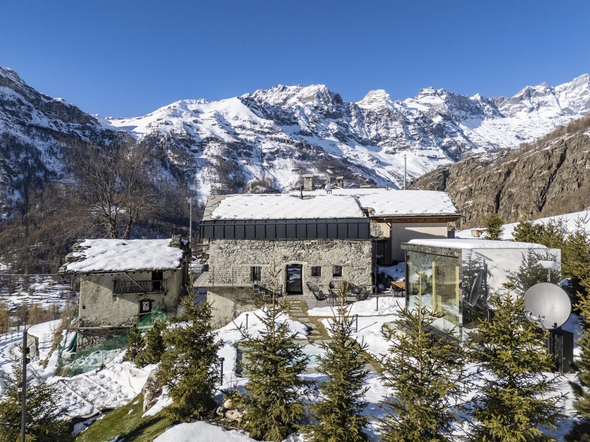 Stone chalet exterior with glass-walled sauna and mountain views
