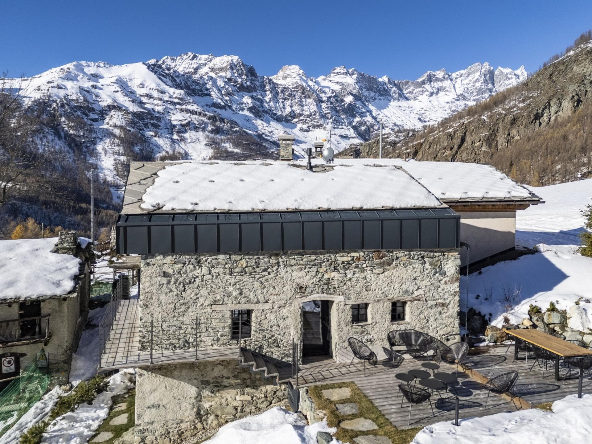 Stone chalet exterior with sun deck and panoramic Alpine views