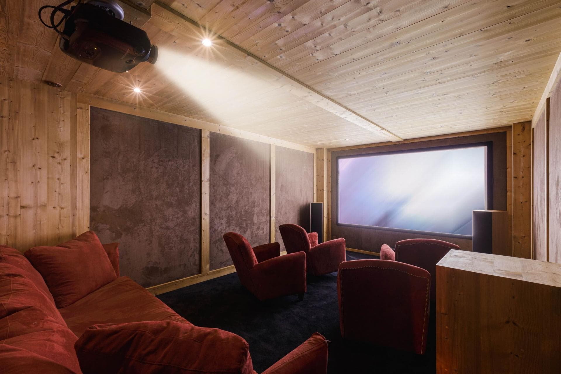 Private cinema room with overhead projector and velvet armchair seating