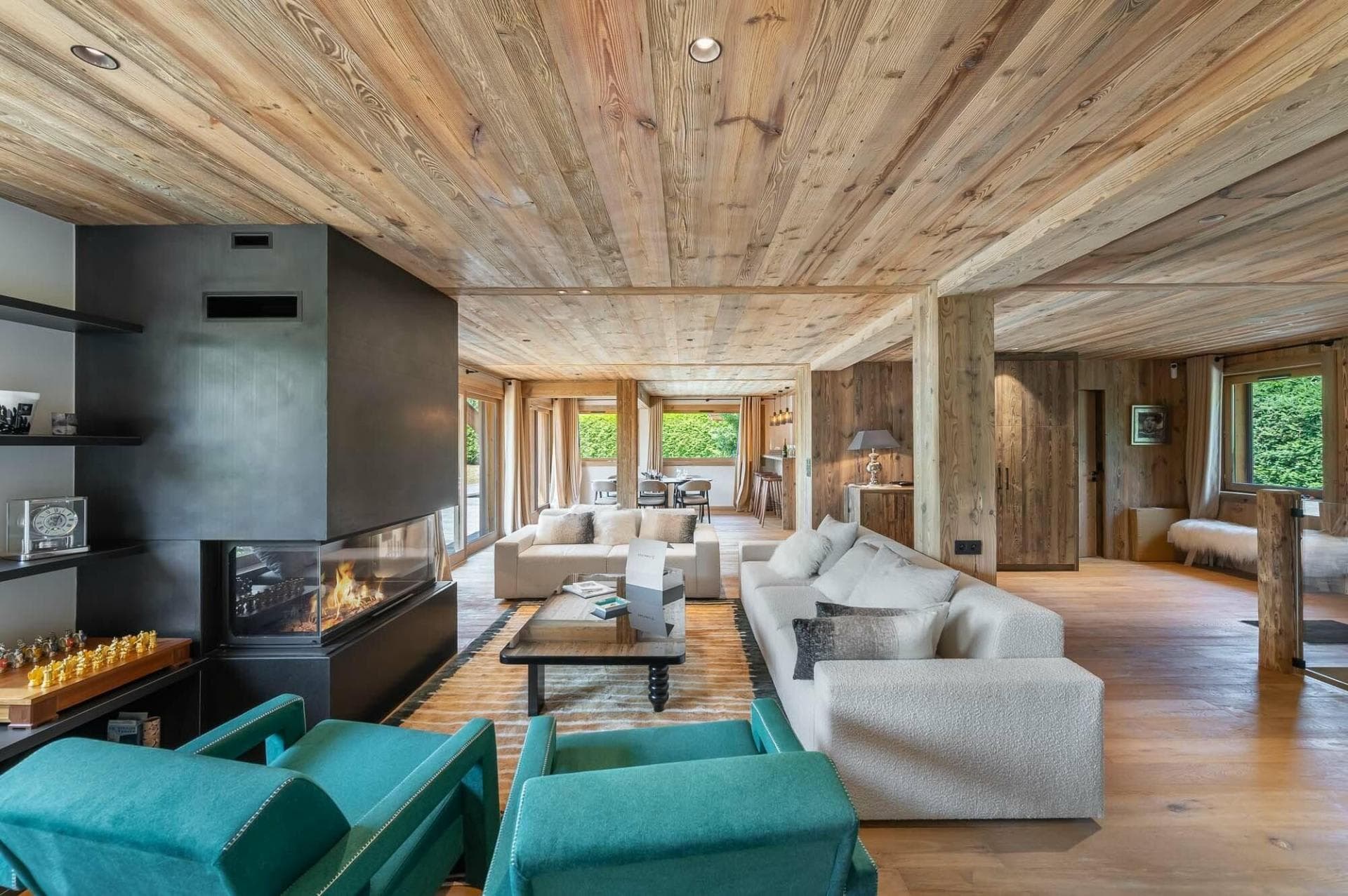 Open-plan living area with three-sided fireplace and reclaimed wood ceilings