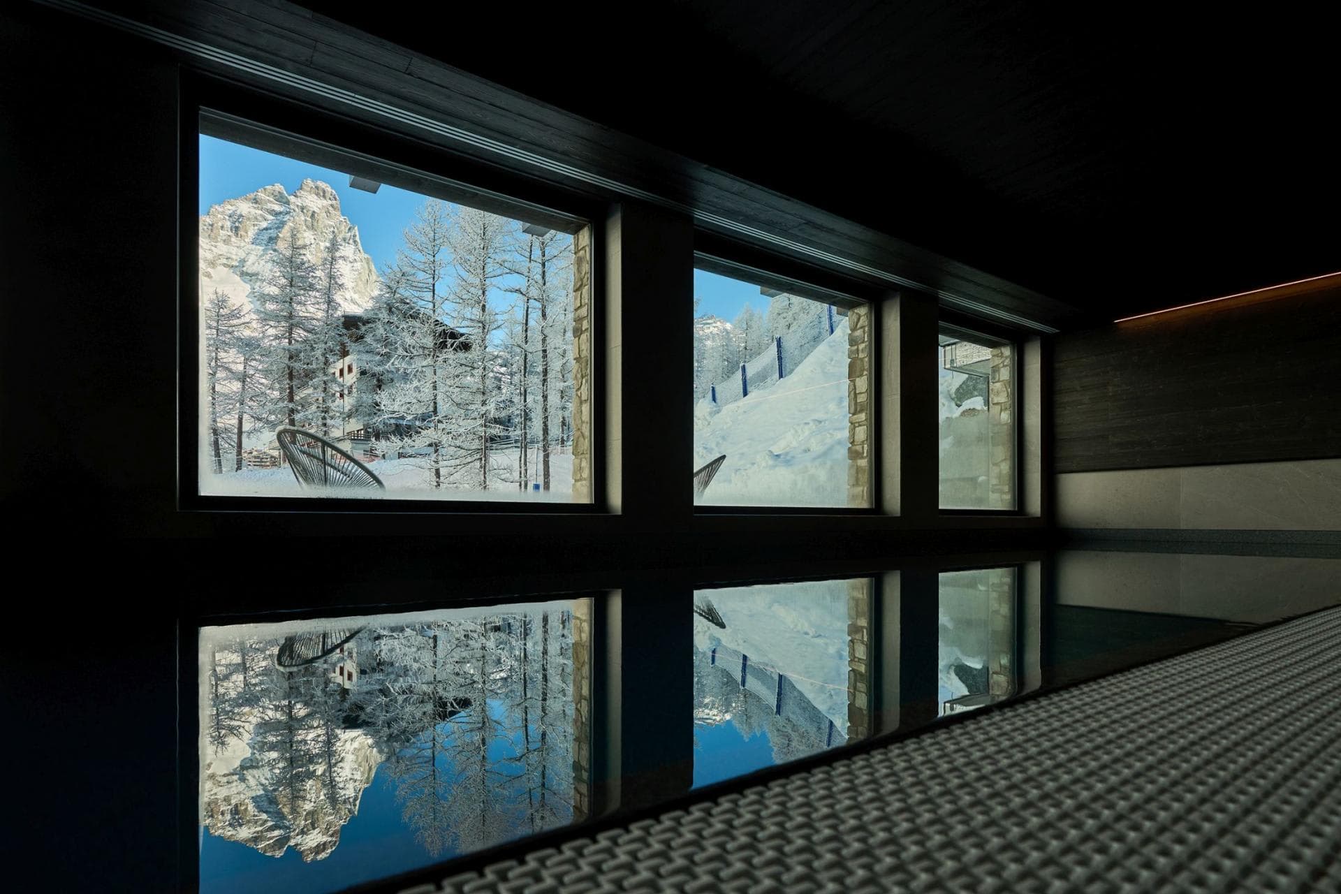 Indoor heated pool with panoramic mountain views through floor-to-ceiling windows