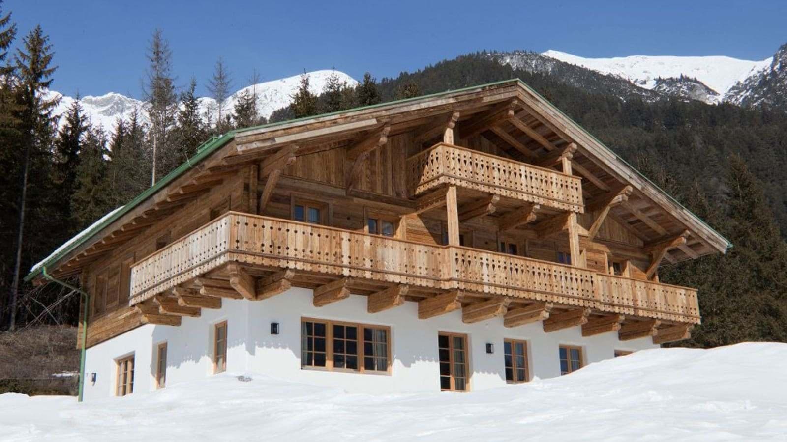 Timber chalet with wrap-around balconies and snow-capped mountain backdrop