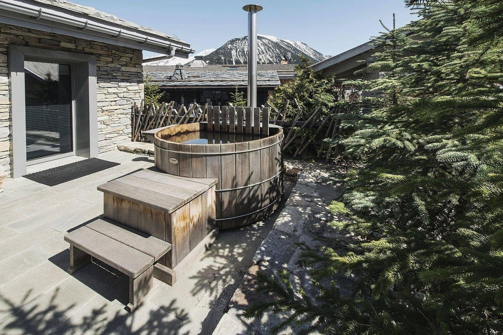 Wood-fired cedar hot tub on stone patio with mountain views