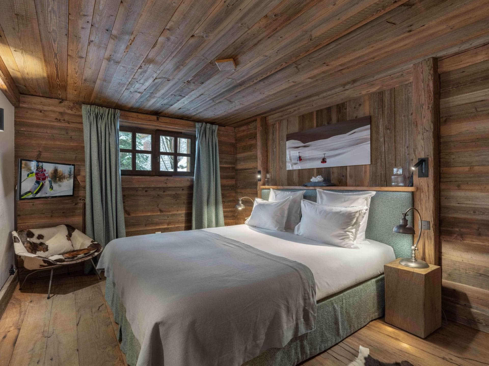 Wood-paneled bedroom with king bed and cowhide reading chair