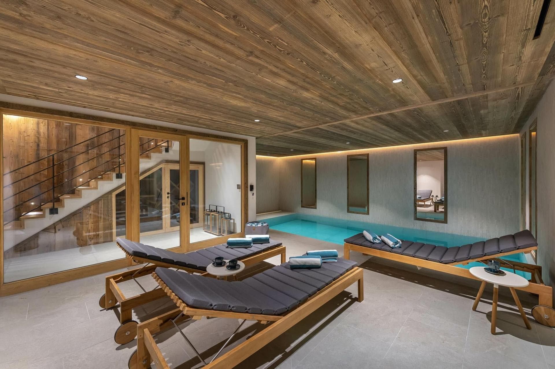 Indoor pool and spa area with three wooden loungers and wood-paneled ceiling